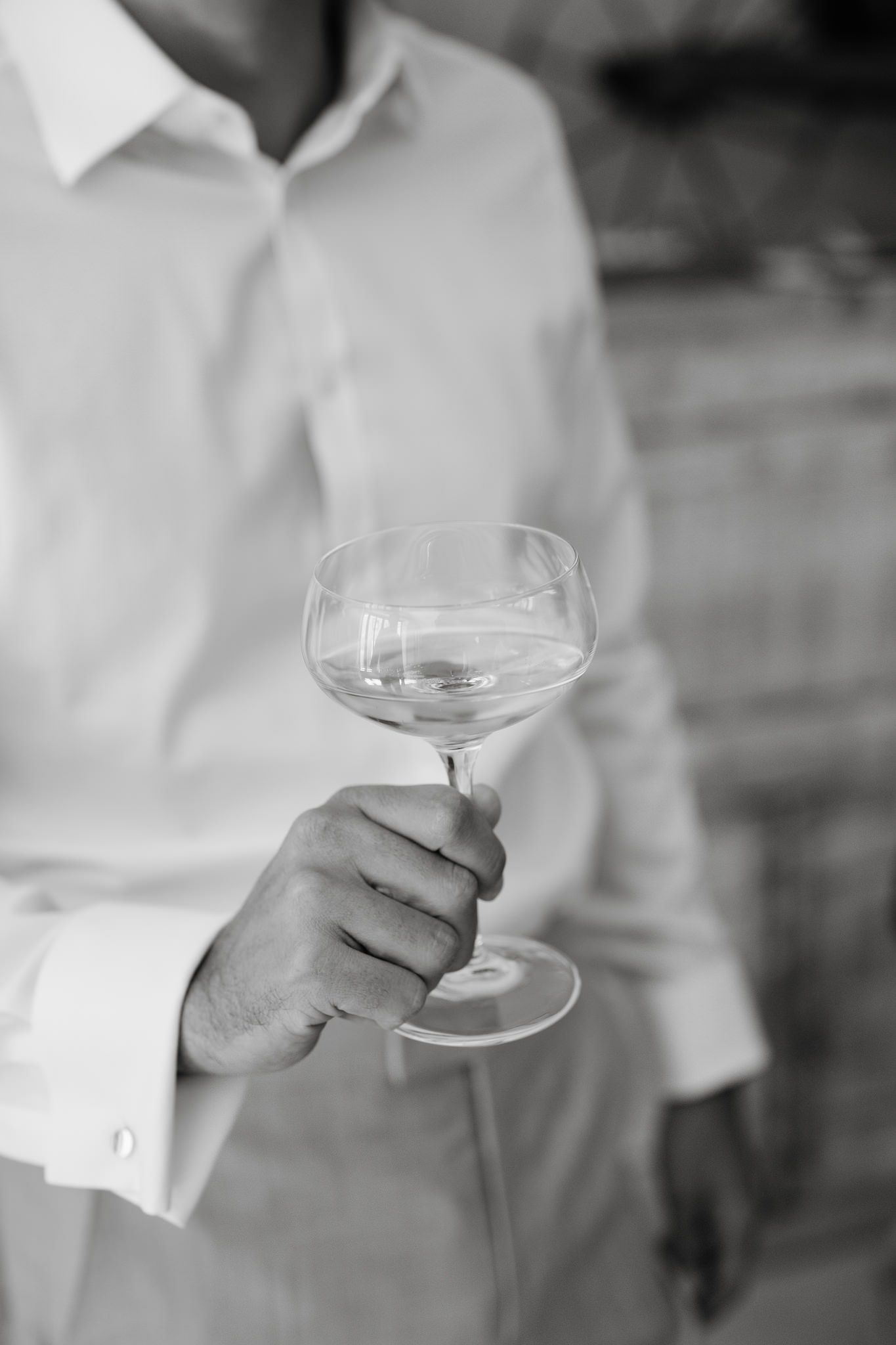 Hands holding elegant champagne coupes in black and white photography.