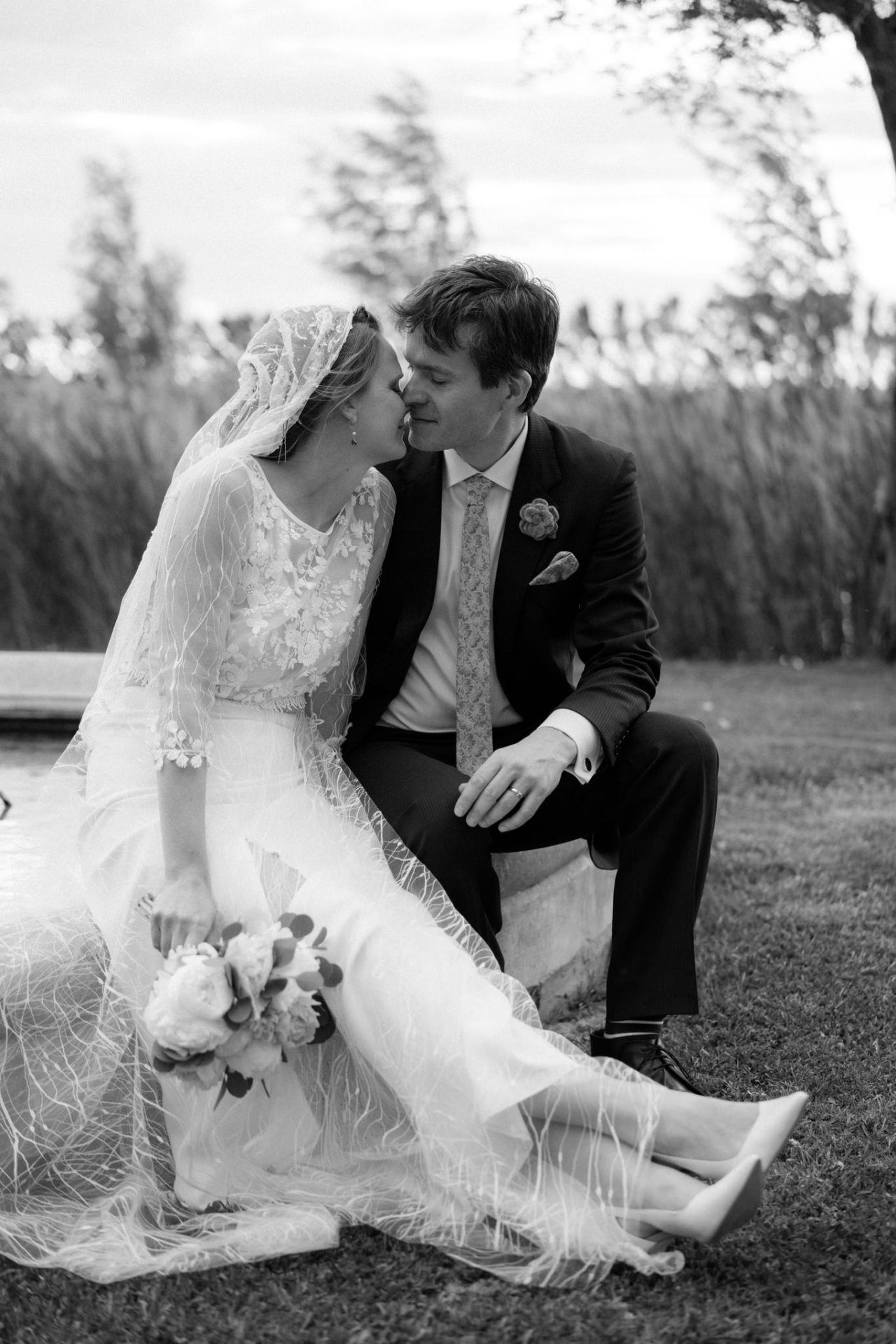 Couple sitting on grass showing off their matching white sneakers.
