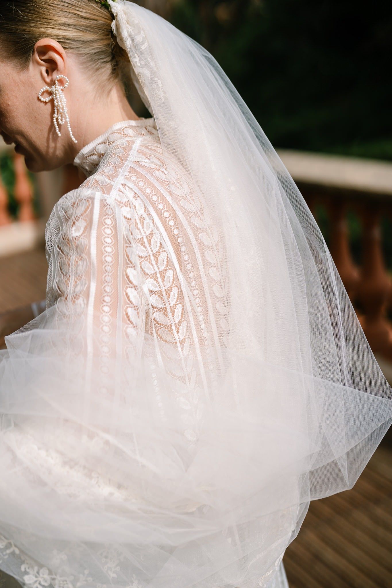 Close-up details of delicate lace wedding dress and flowing veil in natural light.