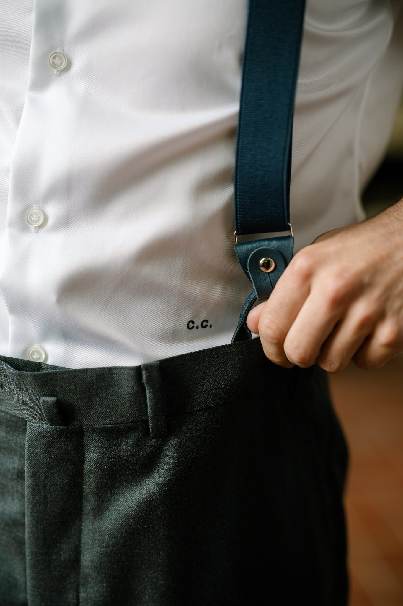 Close-up detail of formal attire showing black suspenders against a white dress shirt.