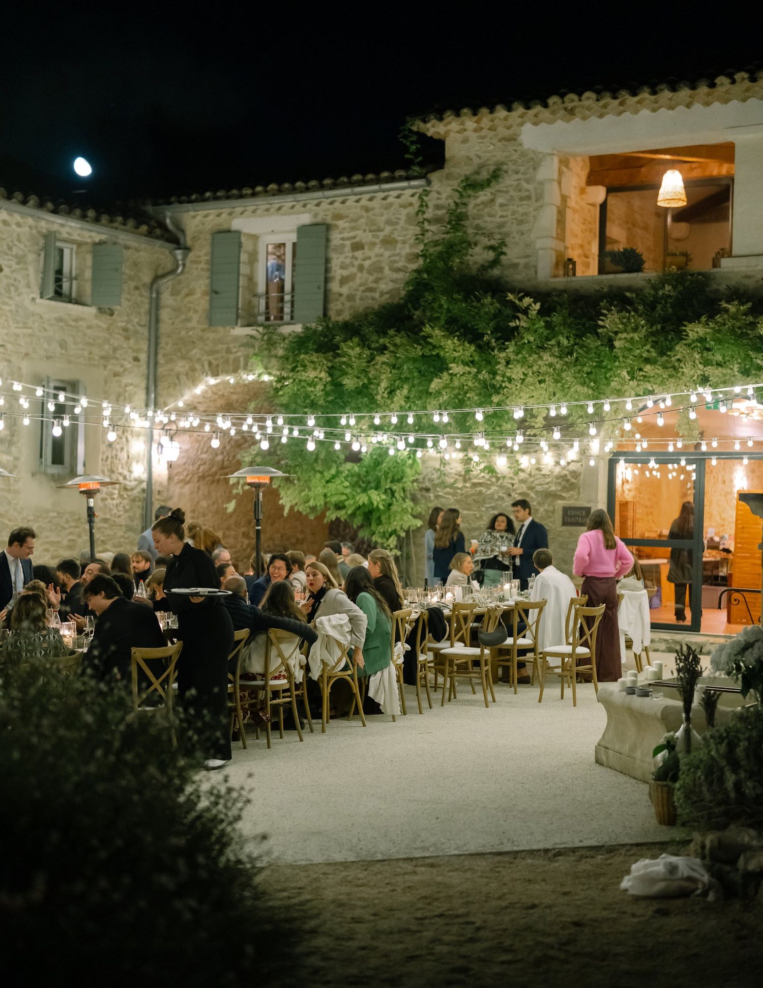 Stone courtyard wedding reception with string lights creating a magical evening atmosphere.