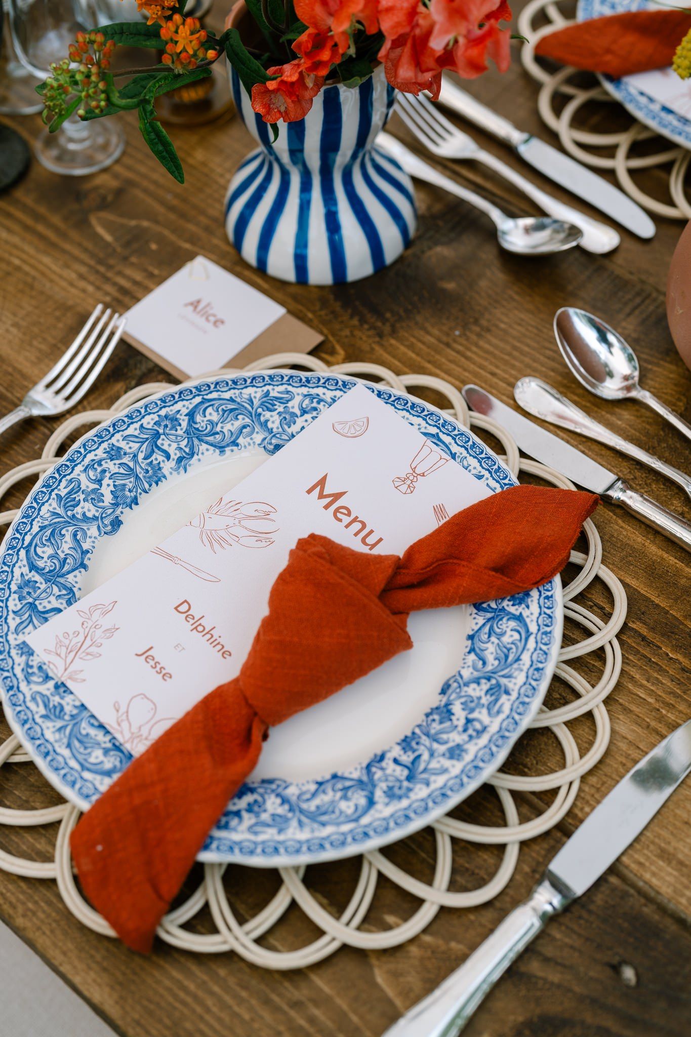 Blue and white patterned plates with red napkins set on a rustic wooden table.