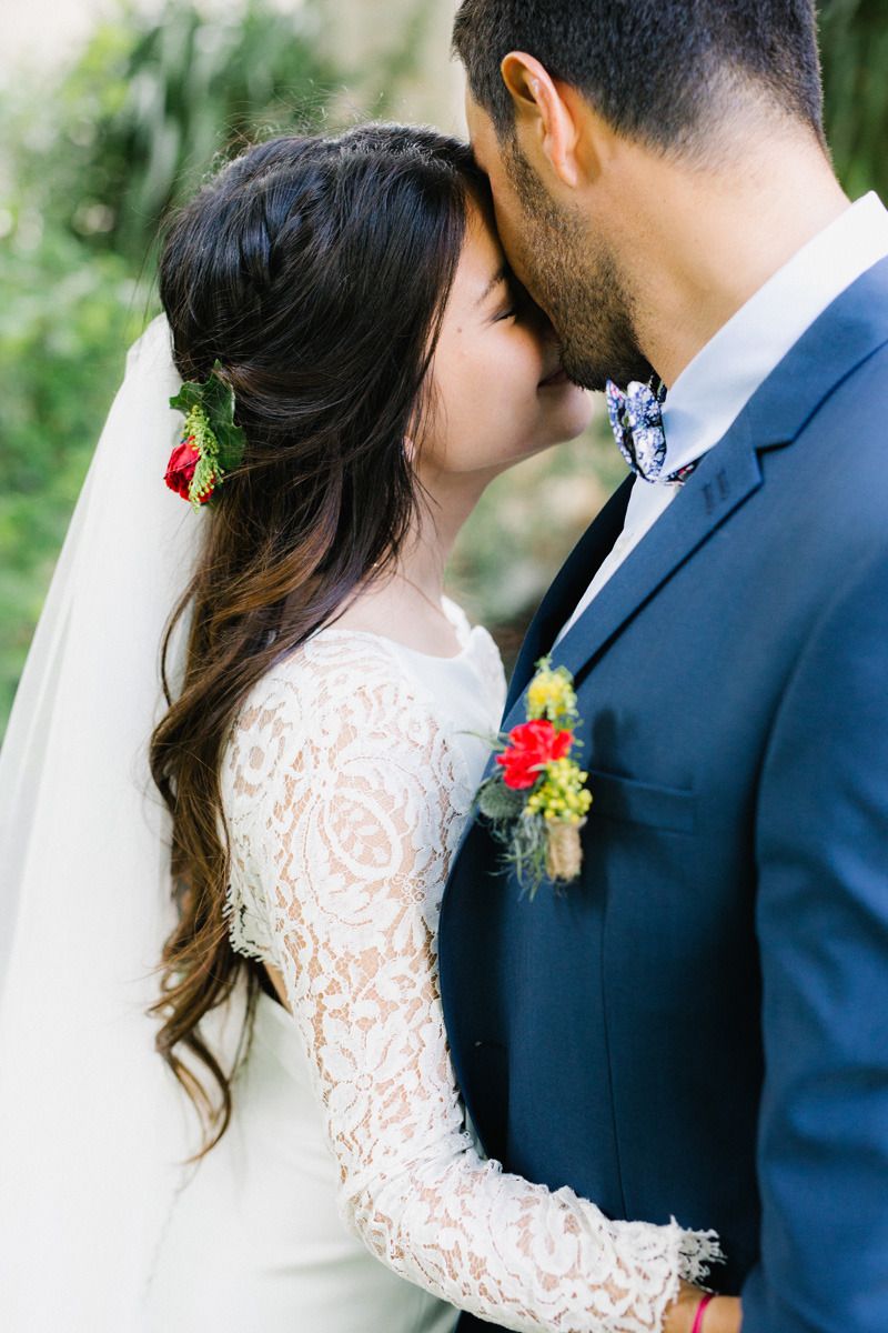 Romantic wedding couple in lace dress and navy suit sharing intimate moments outdoors.