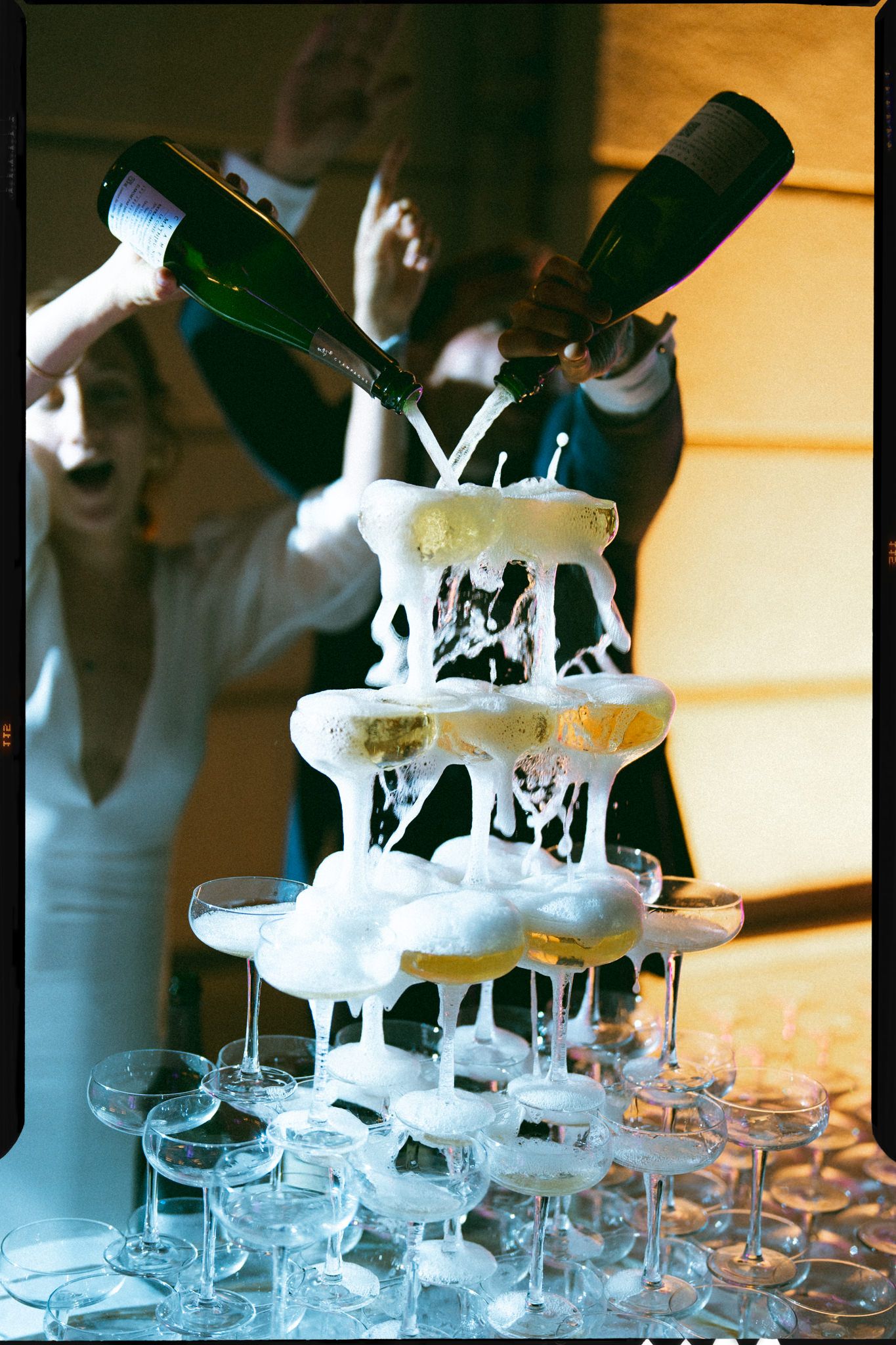 Champagne being poured into a tower of glasses creating a cascading fountain effect.