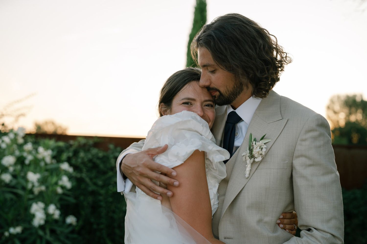 Tender embrace between newlyweds during golden hour portrait session.