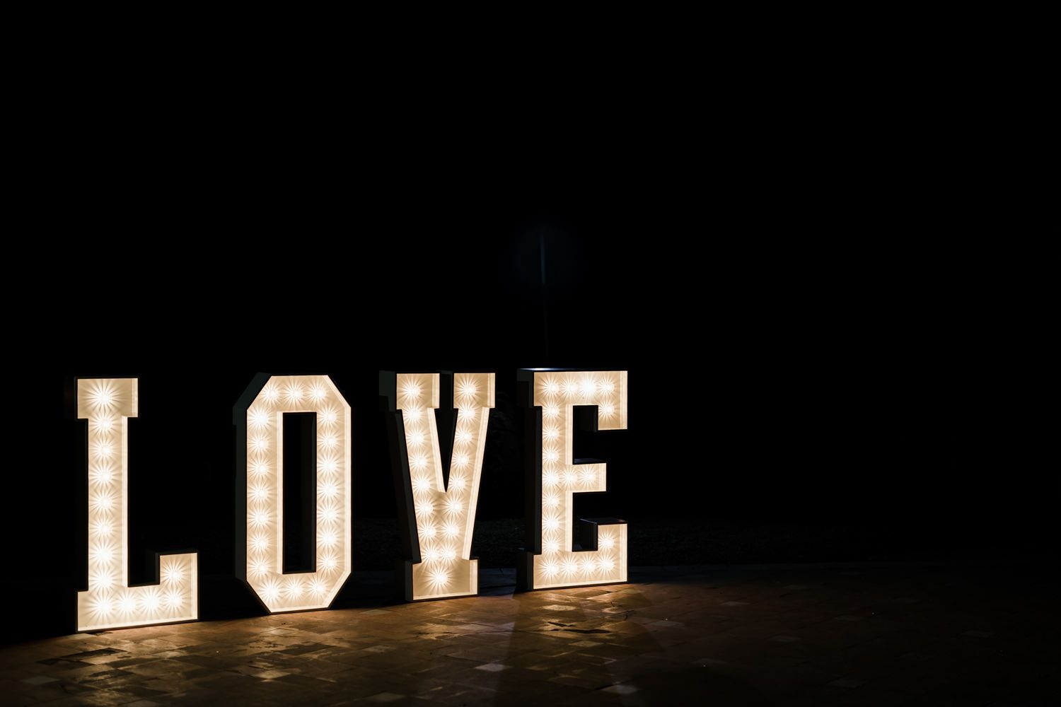 Large illuminated LOVE letters displayed at a wedding reception venue.
