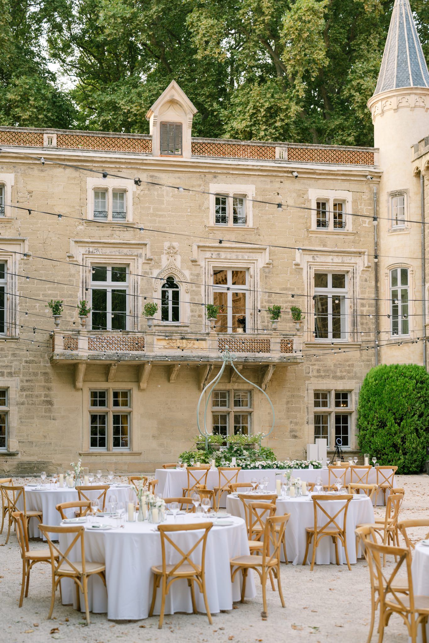 Outdoor wedding reception venue with stone castle-like architecture and string lights.