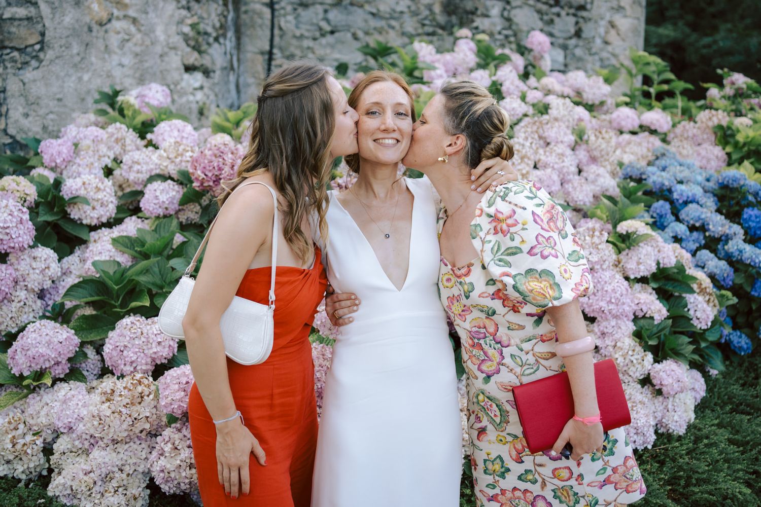 Friends celebrate among blooming pink and blue hydrangea flowers in a garden setting.