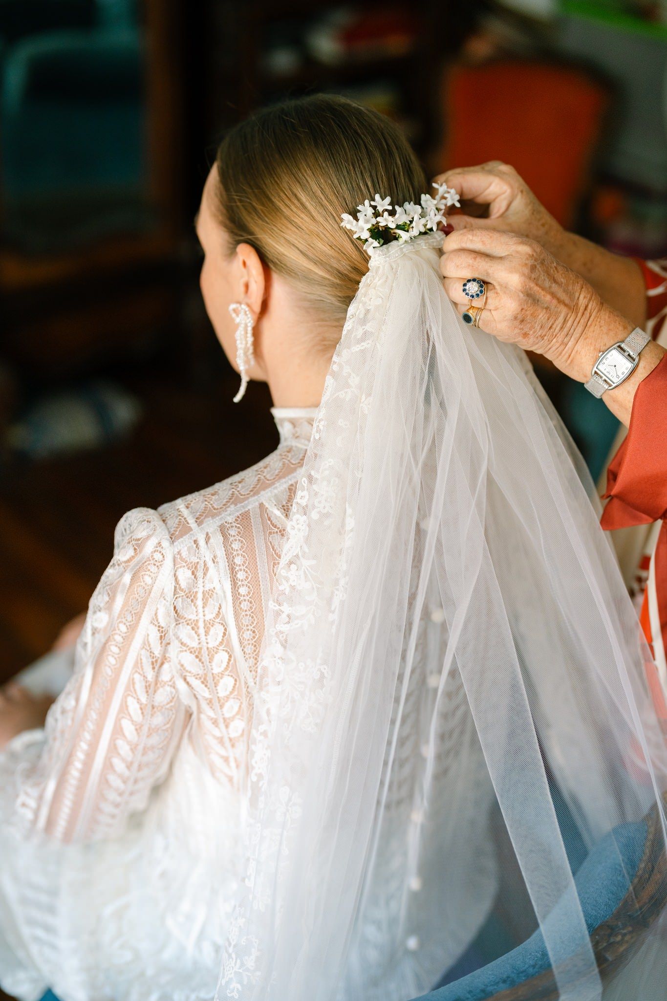 Close-up of intricate bridal veil being secured with crystal hair accessory.