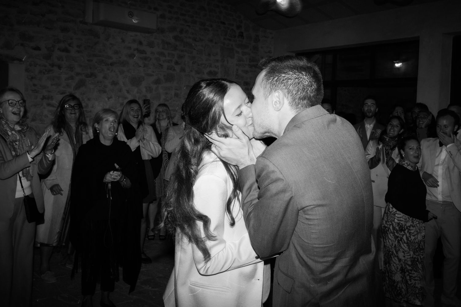 Wedding guests dancing and celebrating on a lively dance floor with string lights overhead.