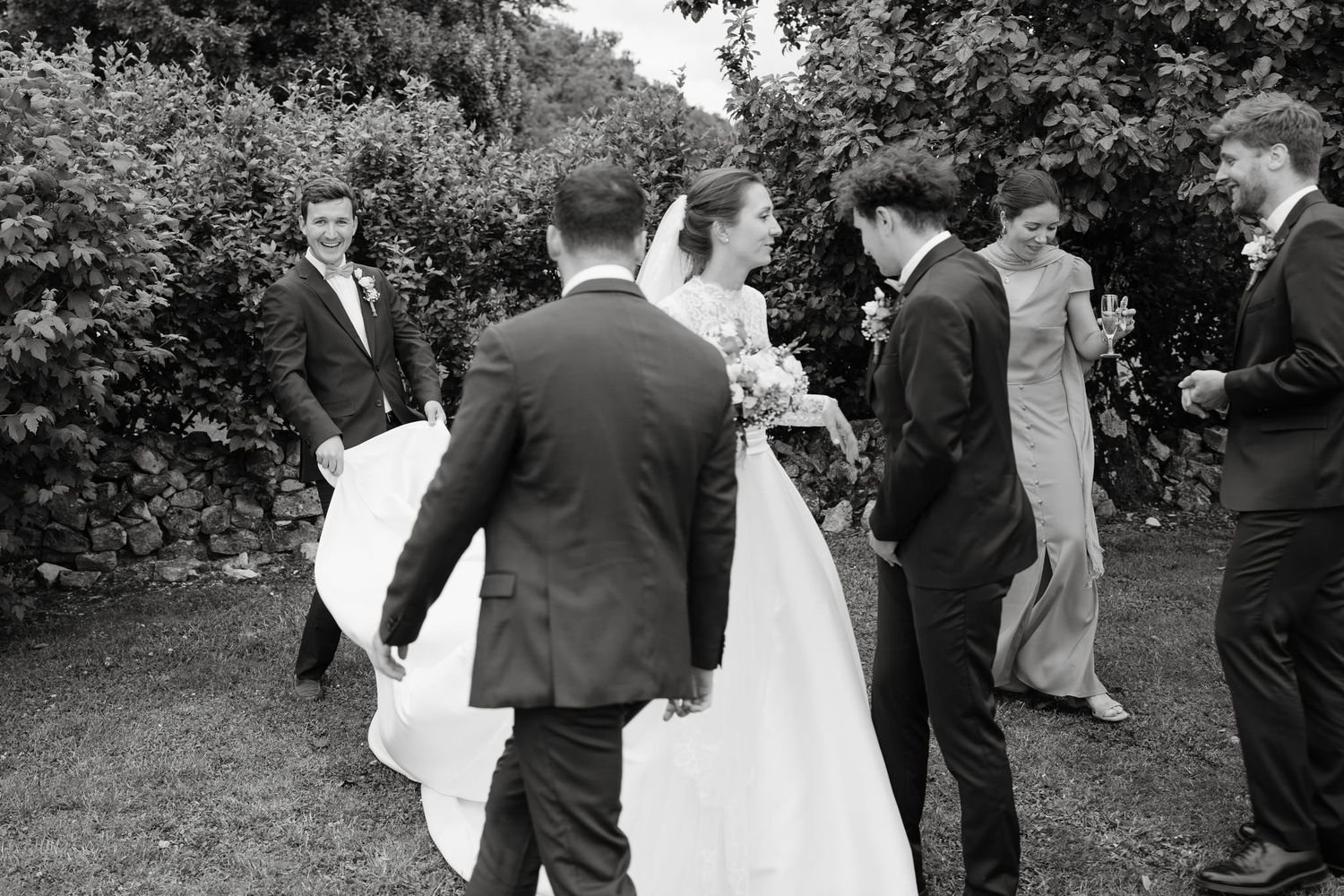 Wedding party guests mingling outdoors in formal attire.