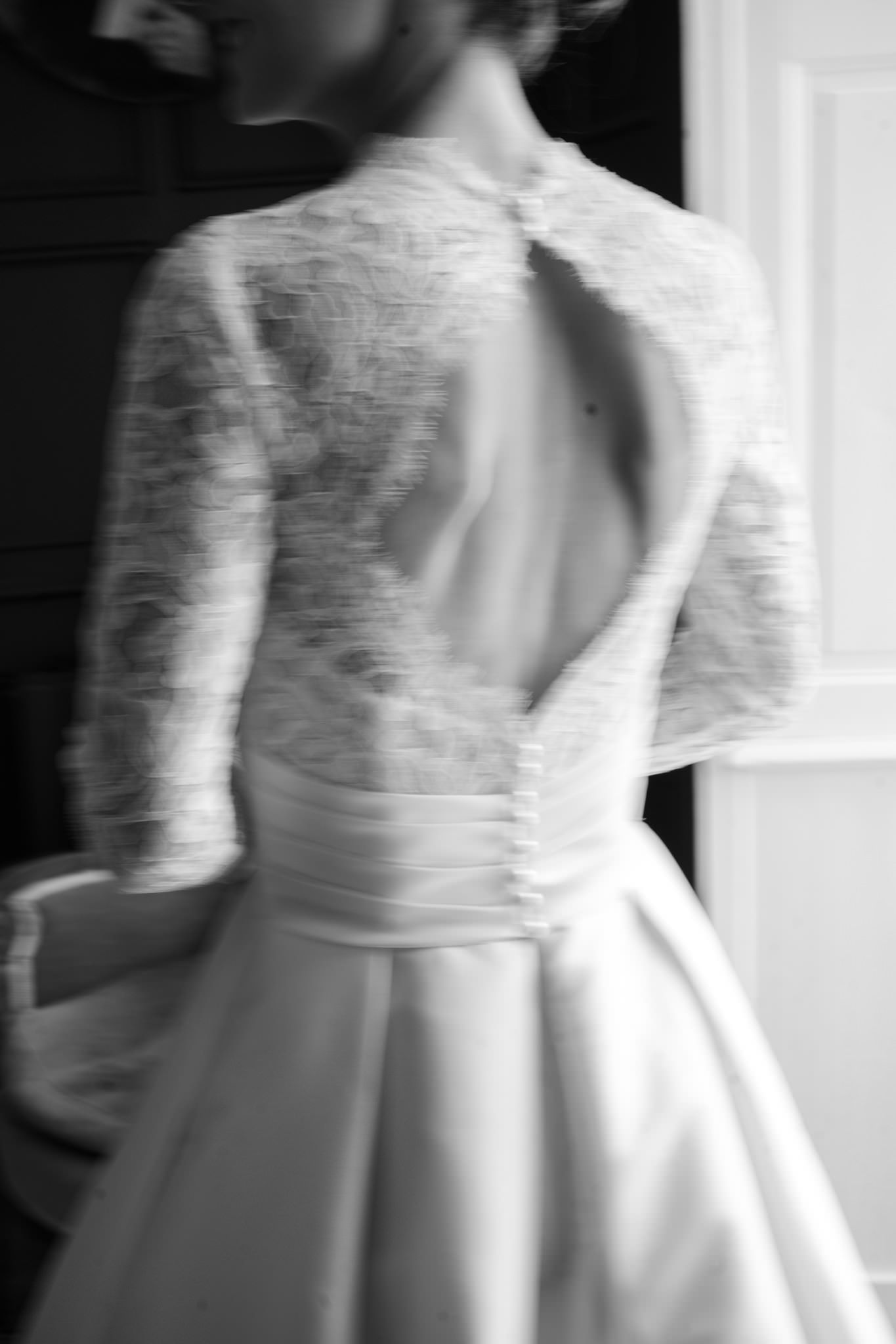 Back details of a white lace wedding gown with buttons and delicate embroidery.