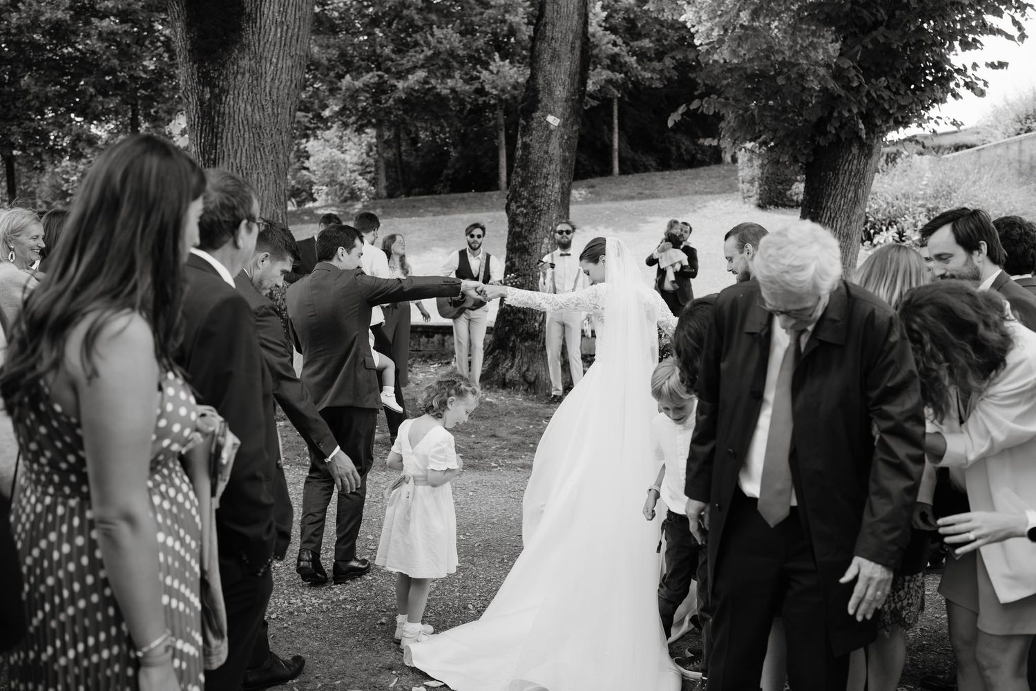 Wedding guests celebrate and cheer during an outdoor reception at a historic venue.