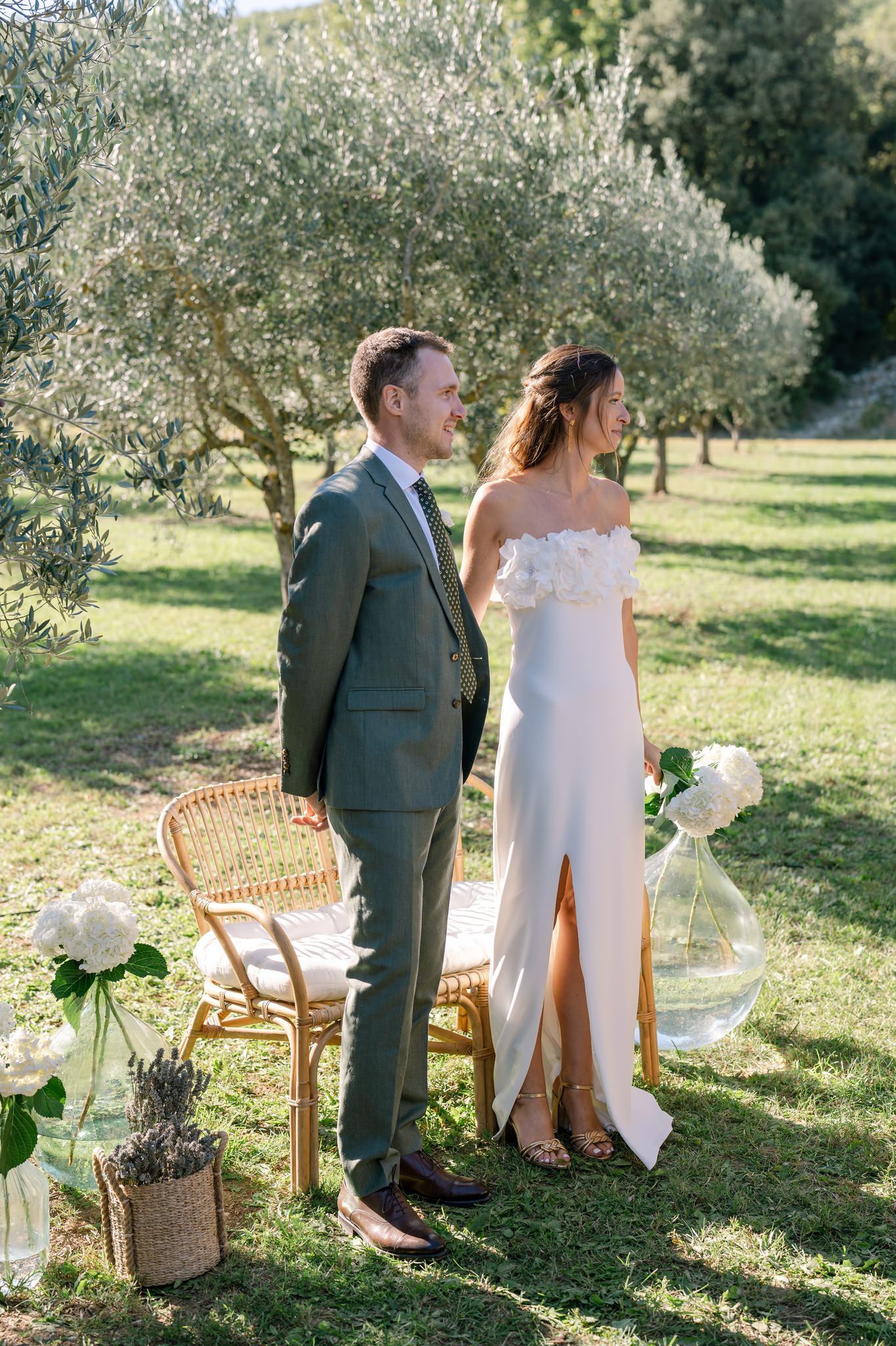 Wedding ceremony setup in an olive grove with wooden chairs and natural decor.