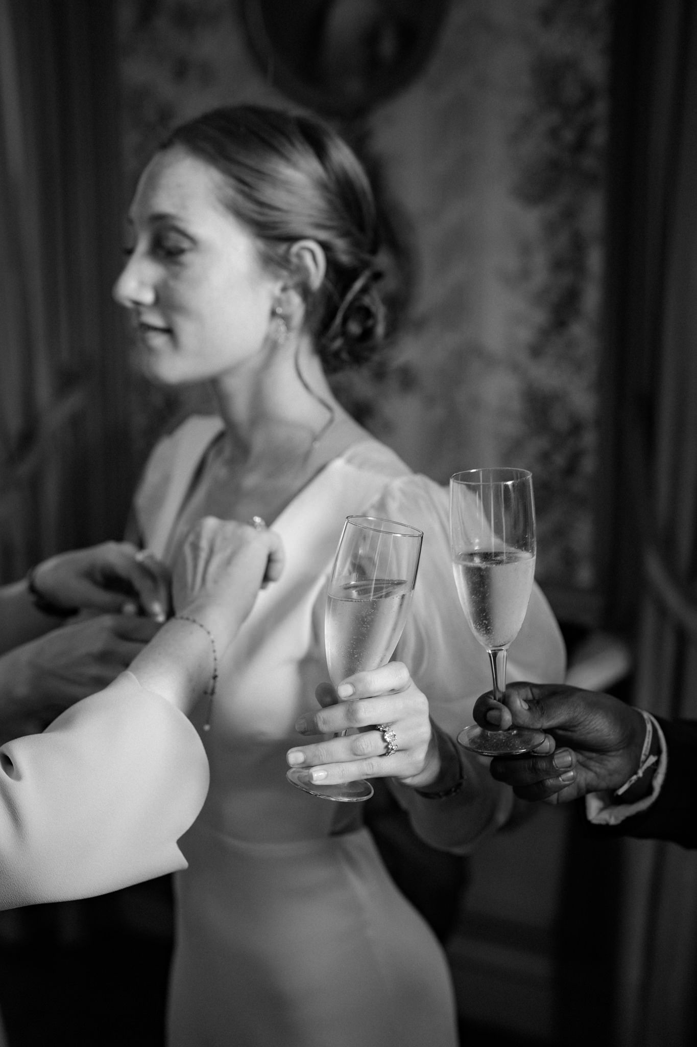 Black and white sequence of a bride in an elegant dress holding a champagne glass.