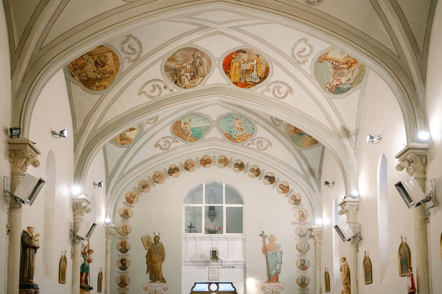 Ornate church ceiling with painted religious murals and arched architecture.