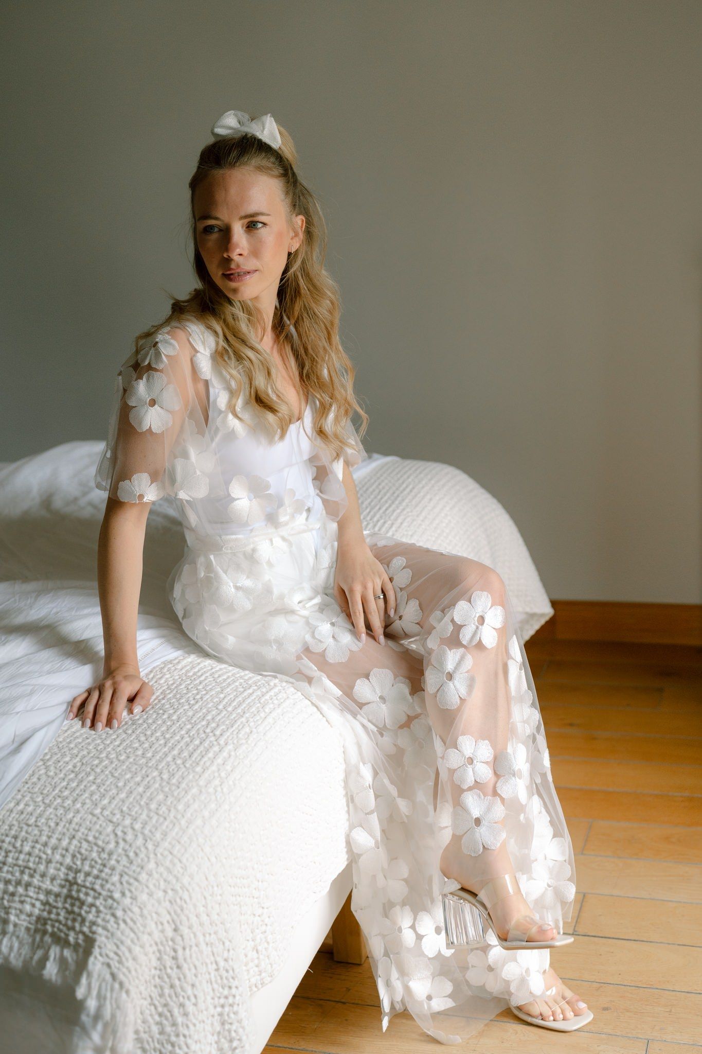 White floral applique dress with delicate butterfly details on a textured background.