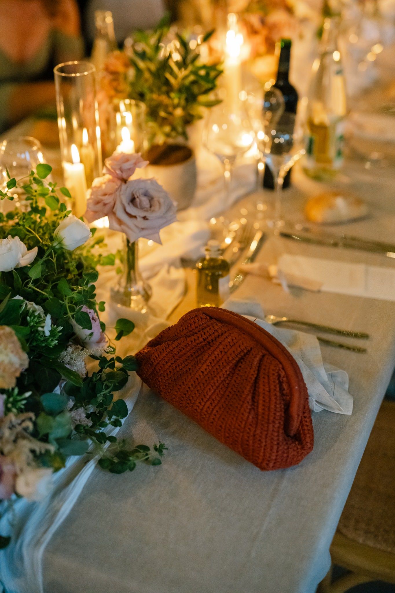 Elegant table setting with candles, greenery and knitted decor creating a warm romantic atmosphere.