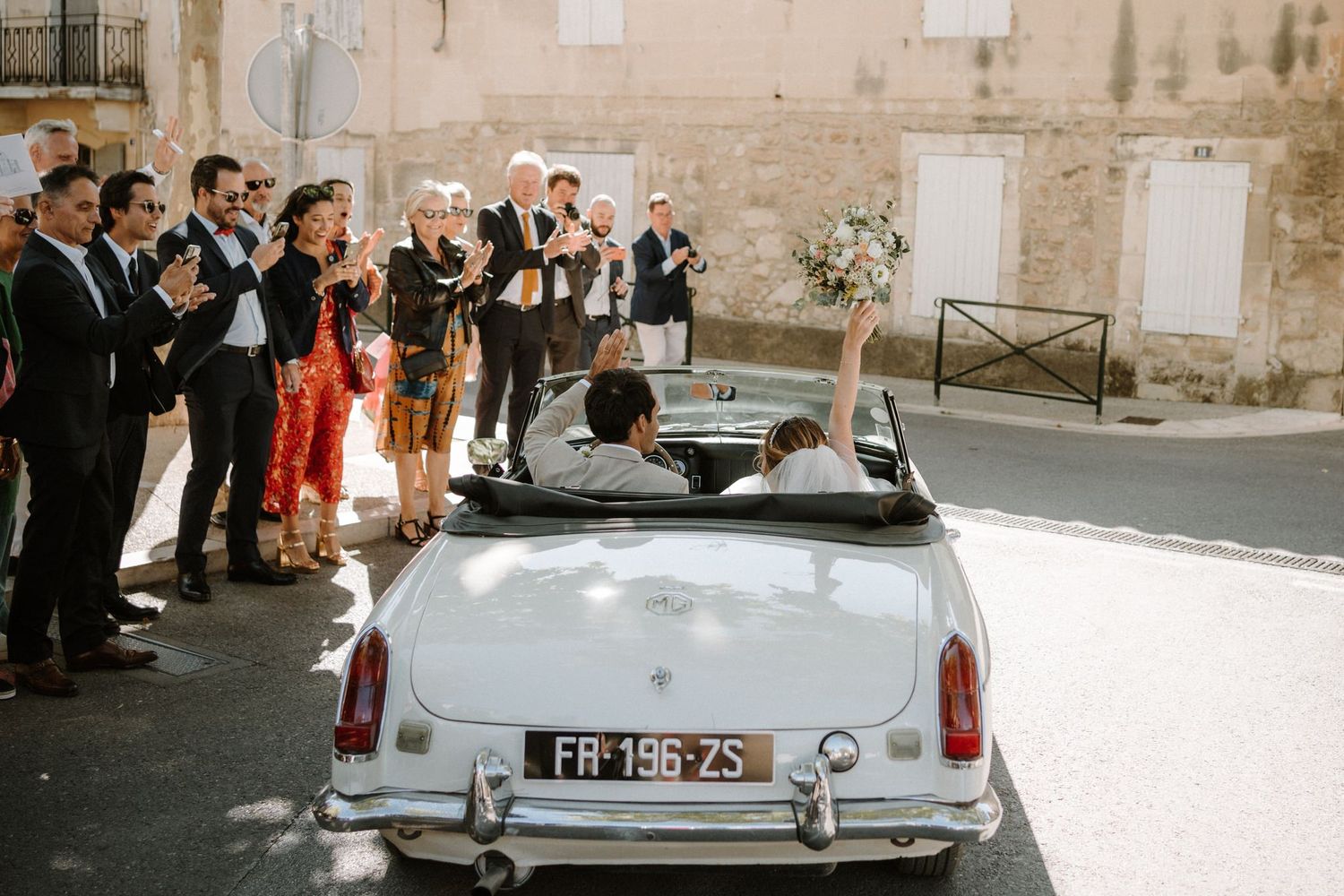 Classic white vintage car decorated for a wedding parked outside a historic stone building.