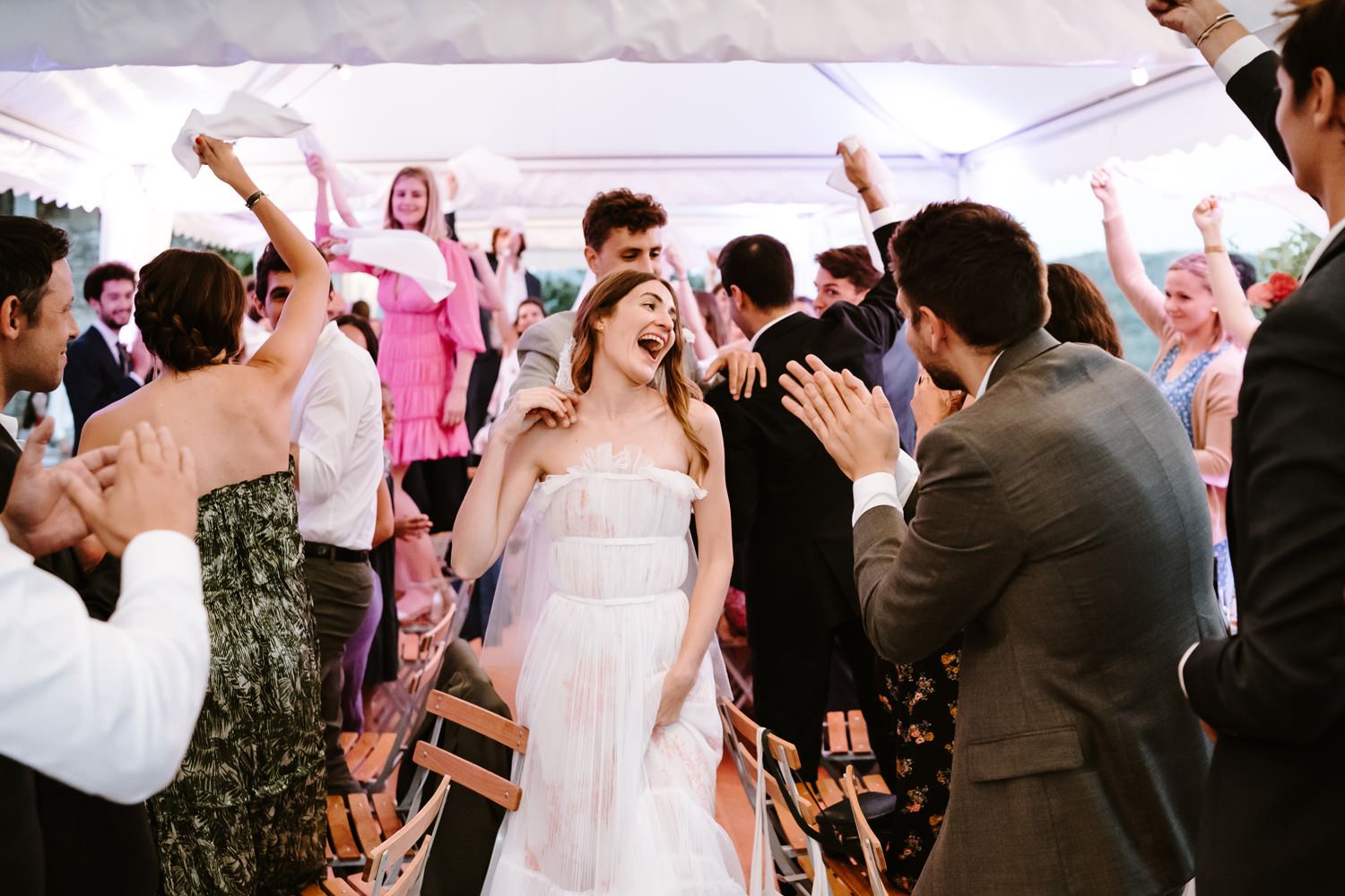 Wedding guests dancing and celebrating at an outdoor reception.