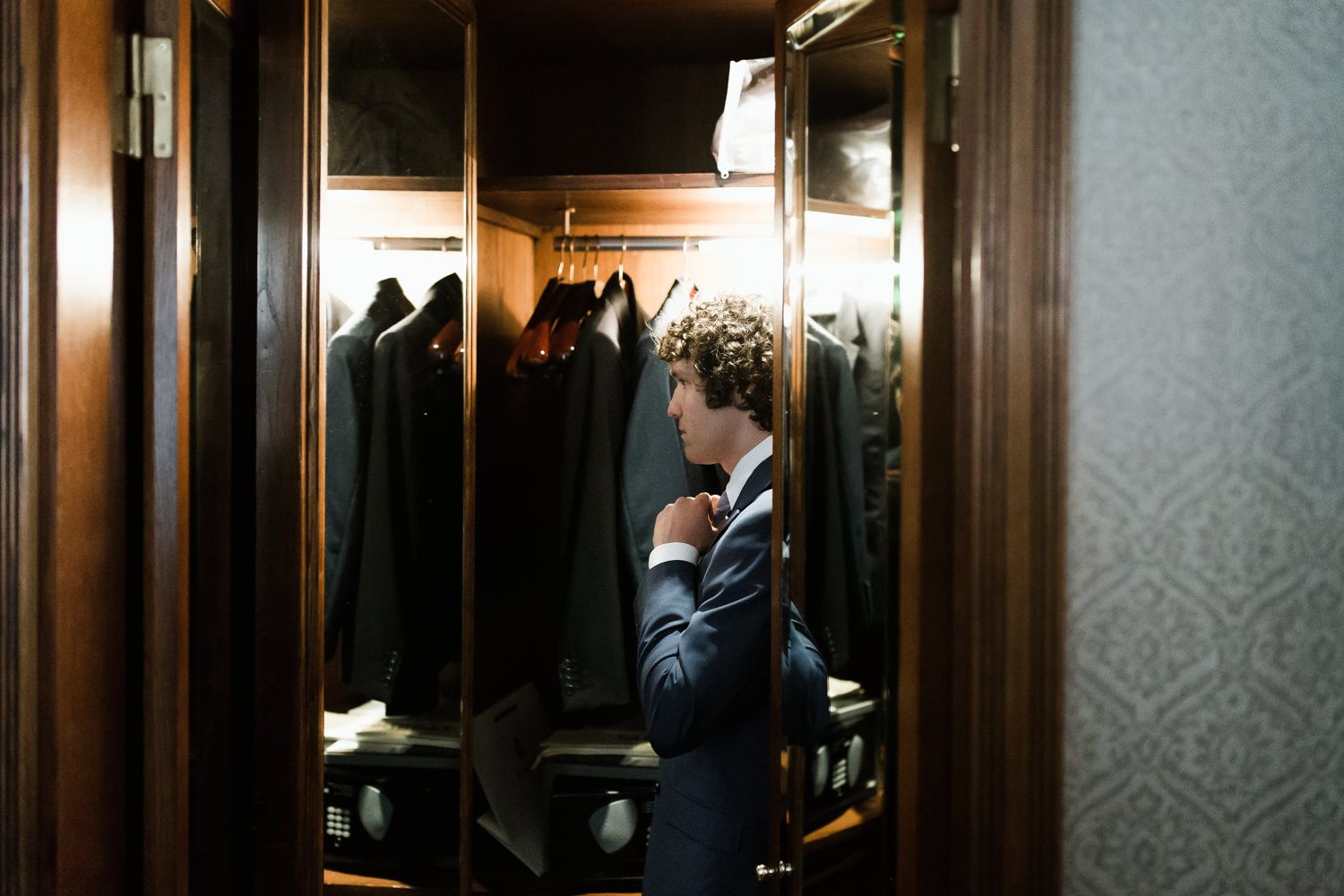 A dimly lit wardrobe room with formal attire hanging.