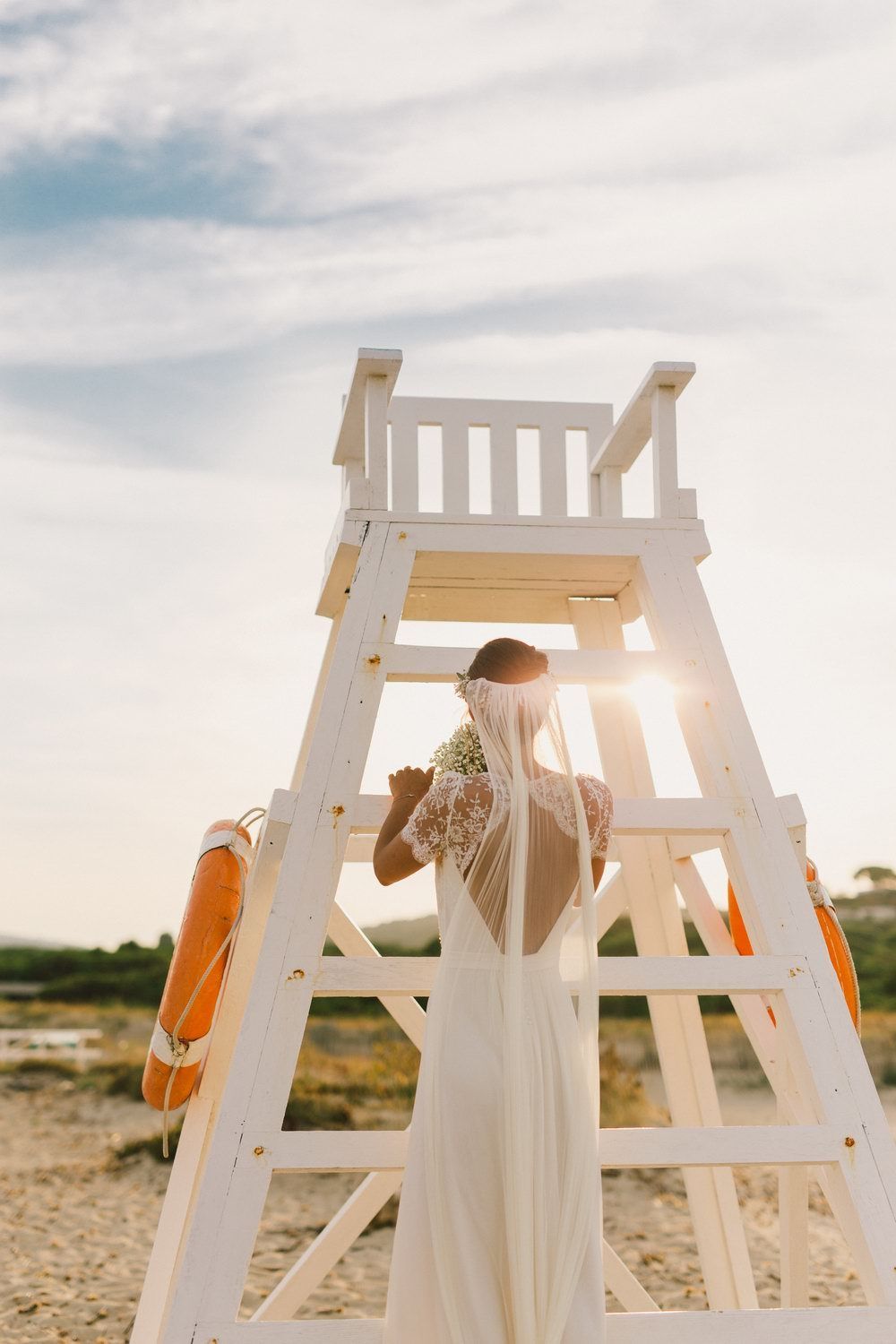White wooden beach chairs arranged on sandy shore at sunset.