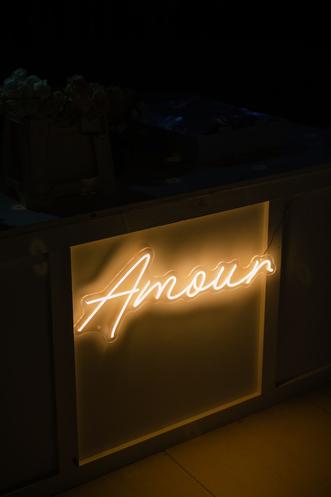 Illuminated 'Amour' neon sign glowing warmly in the dark.