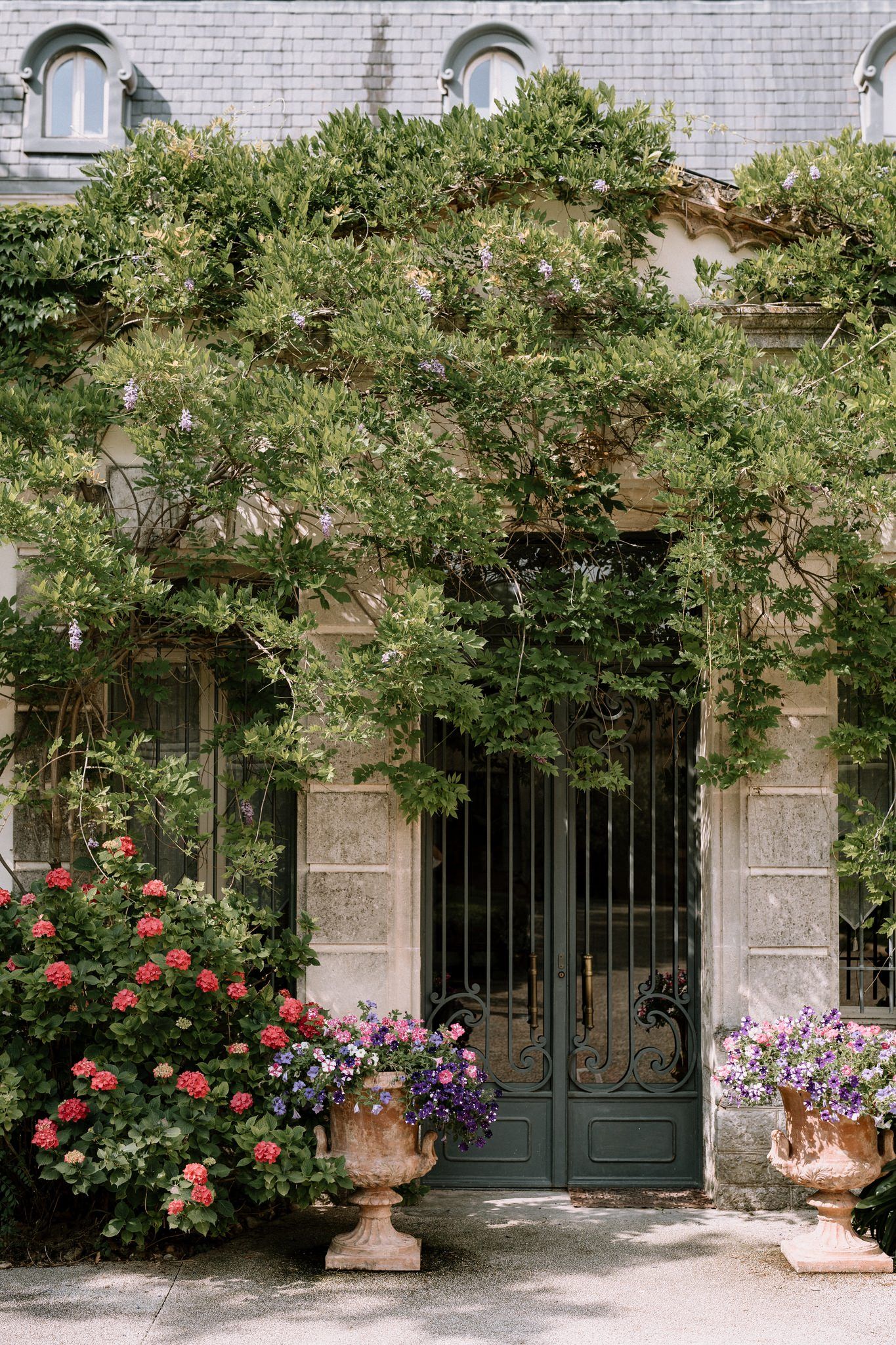 Elegant stone building entrance with climbing roses and decorative iron gates.