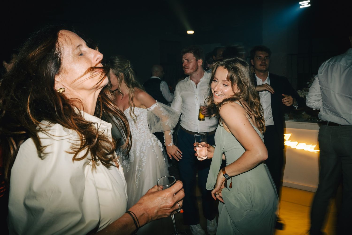 Guests dancing and celebrating at a dimly lit wedding reception party.