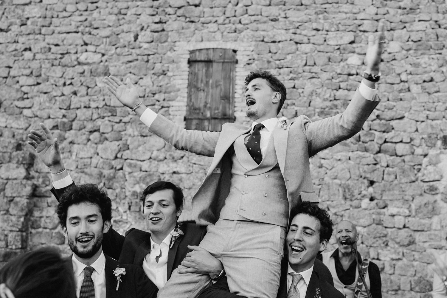 Black and white photo of wedding party celebrating with enthusiasm.