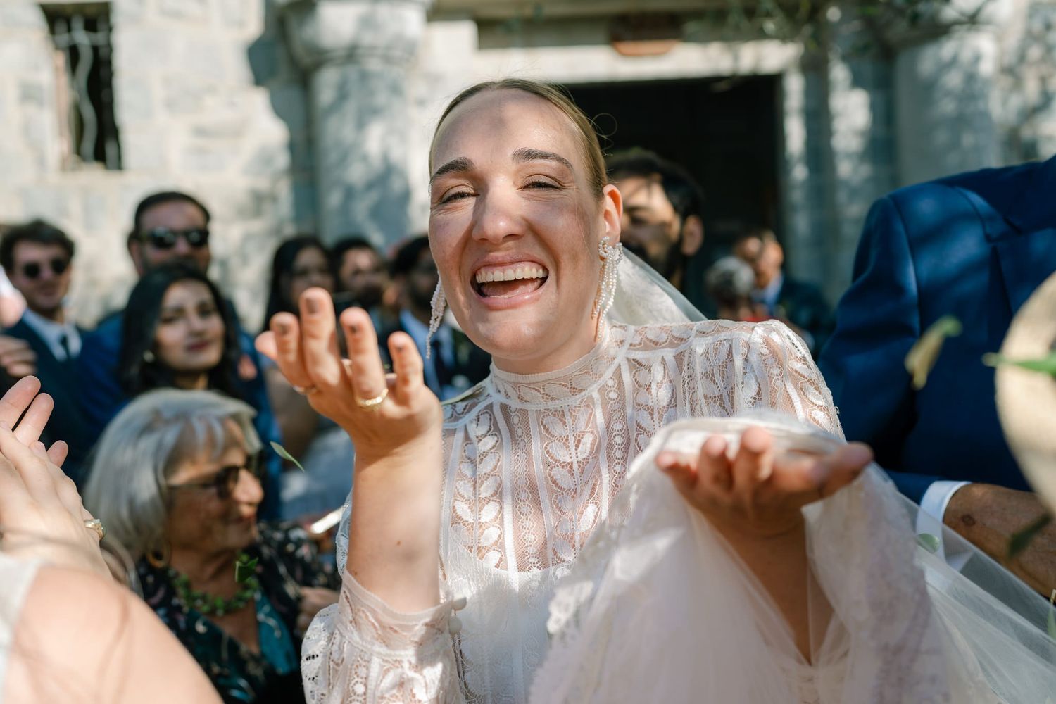 Joyful celebration with guests throwing confetti in natural sunlight.