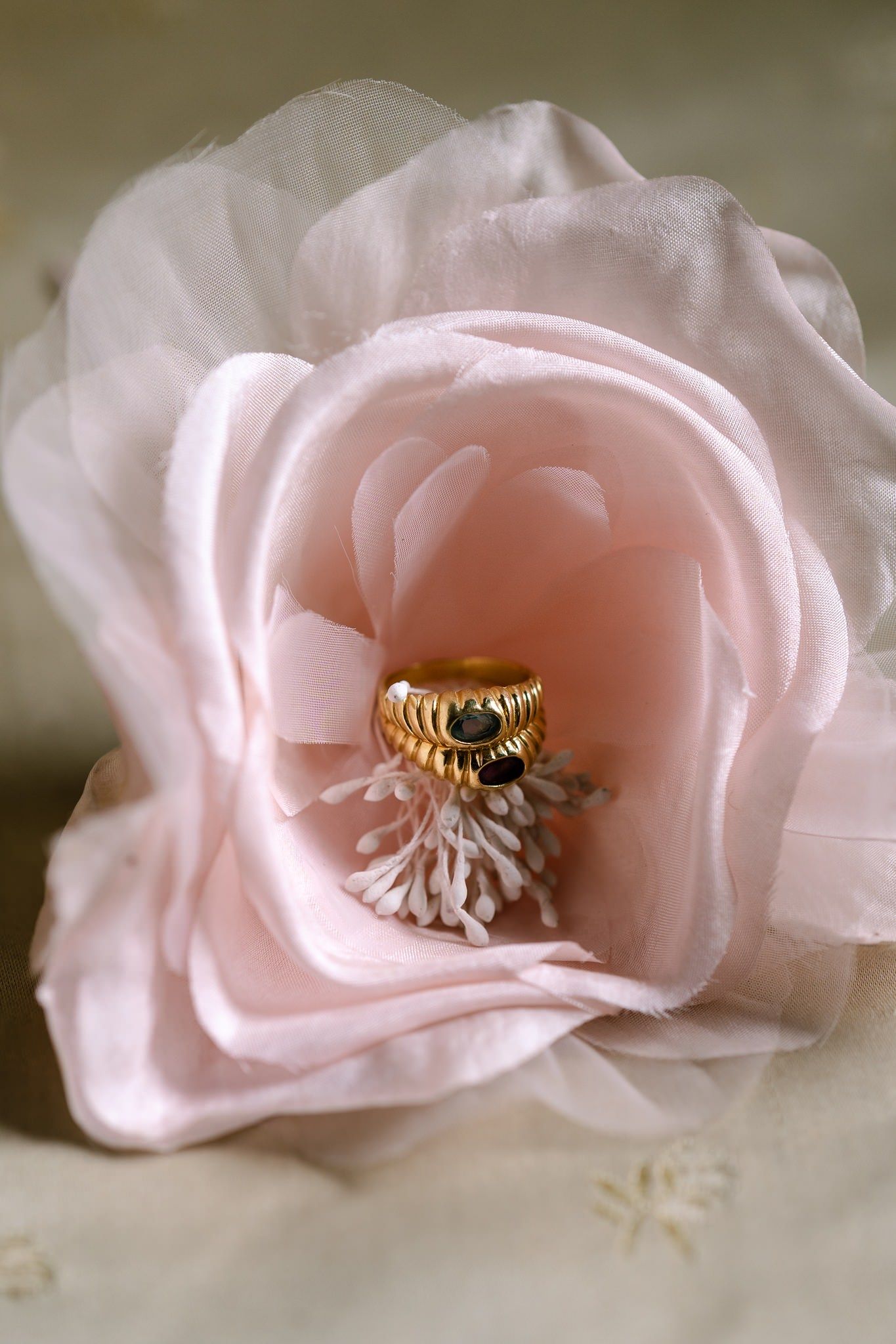 Delicate pink fabric flower with golden ring nestled in its center.