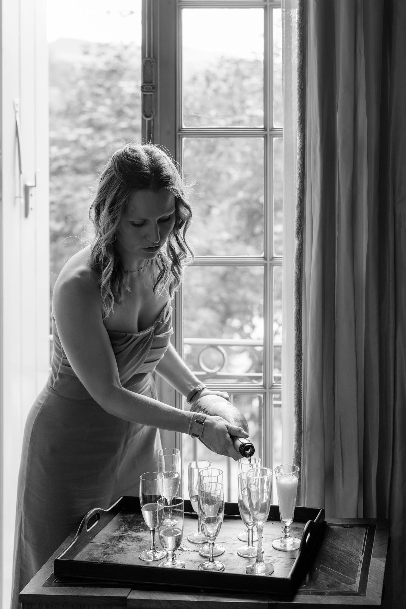 Setting up champagne glasses near a bright window in elegant interior.