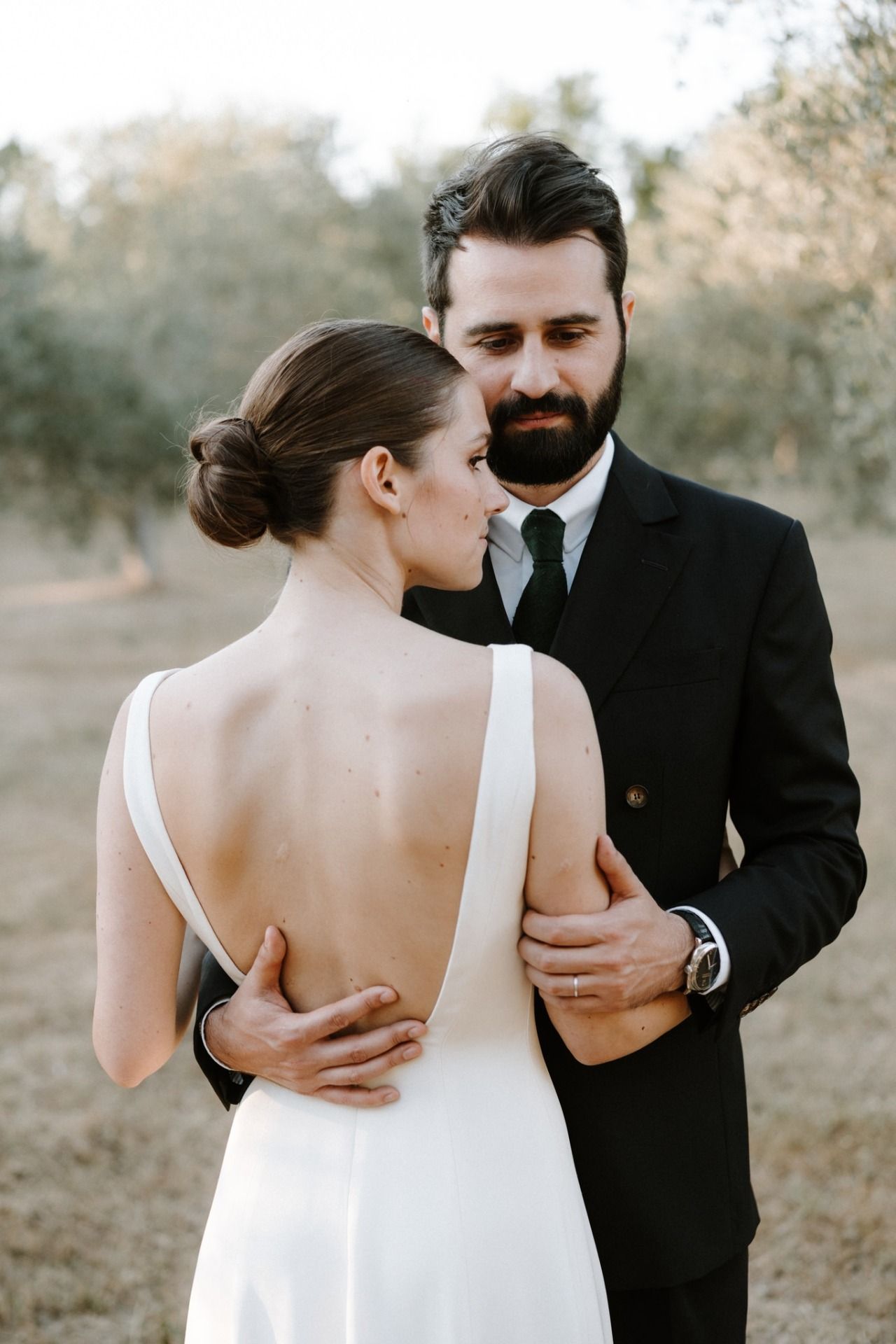 Elegant wedding couple in white dress and black suit during outdoor photoshoot.