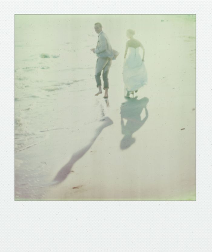 Dreamy vintage-style photo of couple walking along beach shoreline.