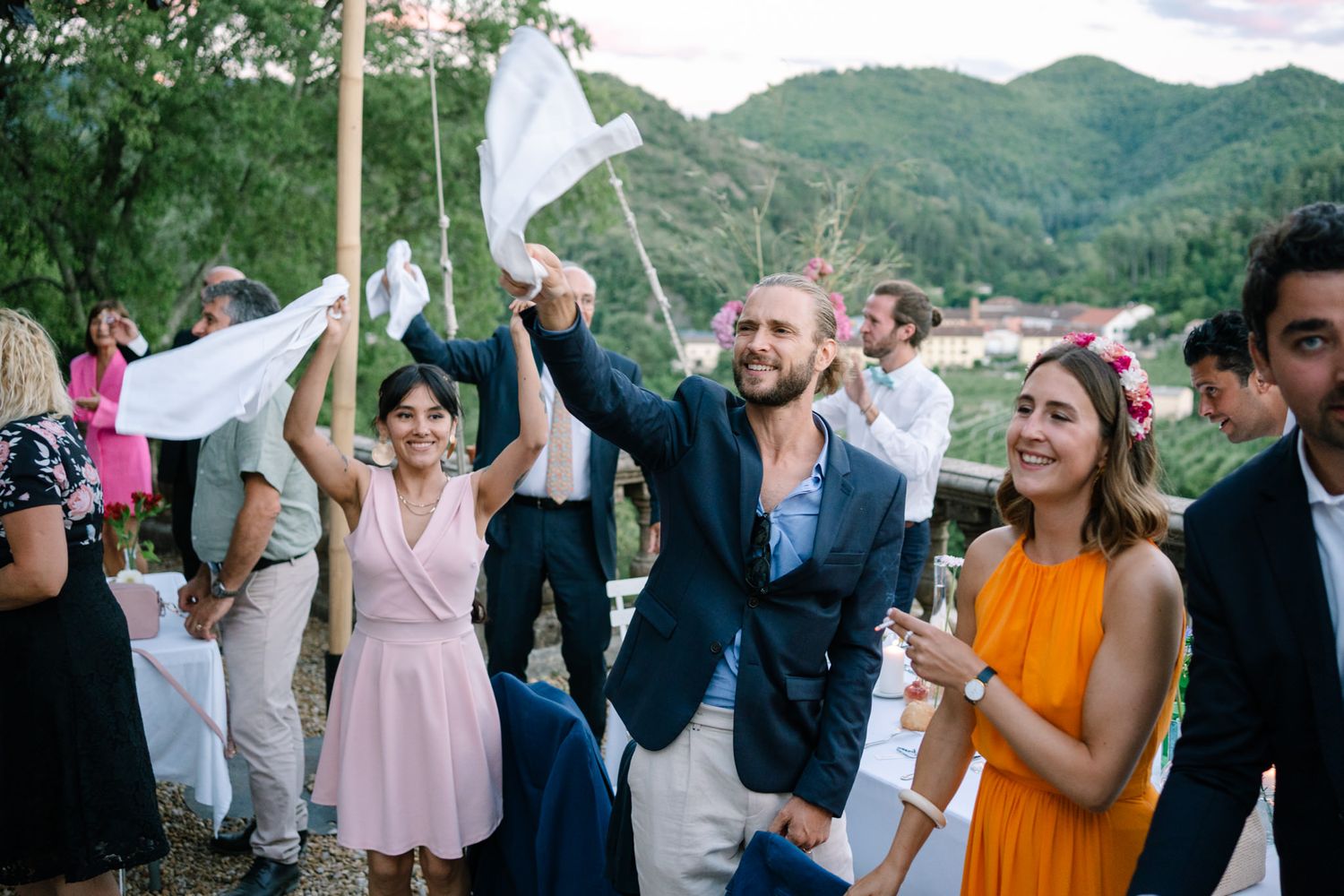 Wedding guests dance and celebrate with mountains visible in background.