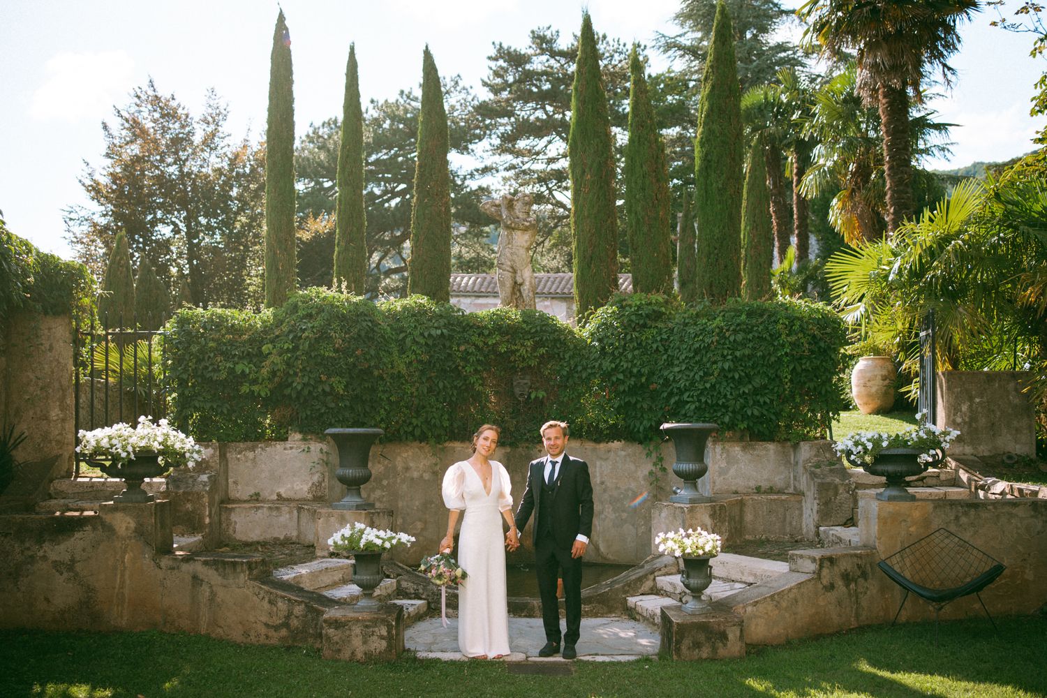Wide angle view of a formal garden with stone pathways and classical architecture.