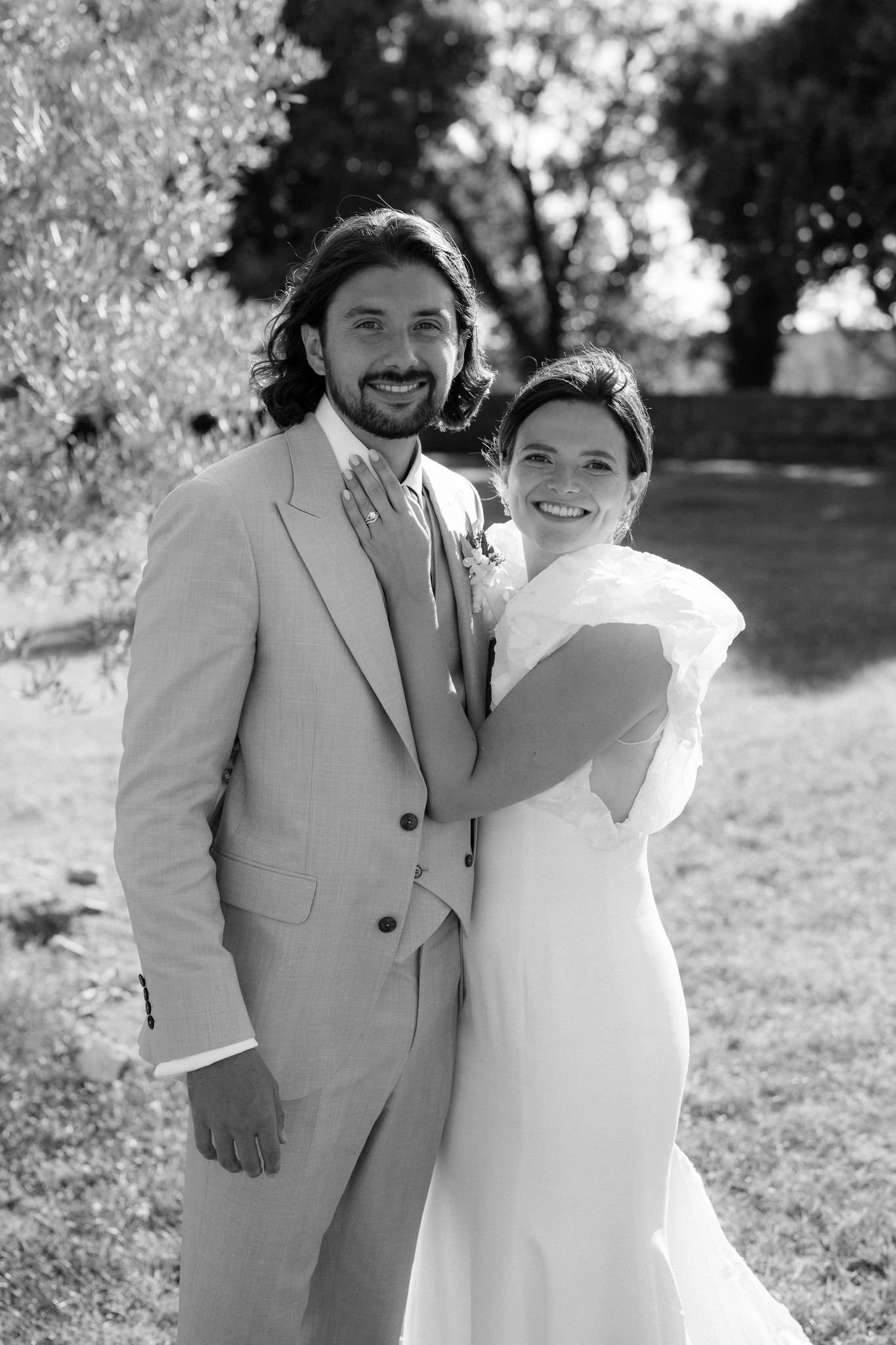 Wedding couple in white and beige attire sharing joyful moments outdoors.