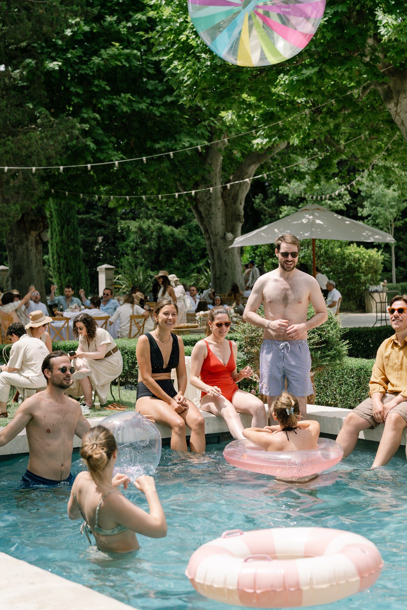 Summer pool party with people enjoying inflatable floats and festive atmosphere.