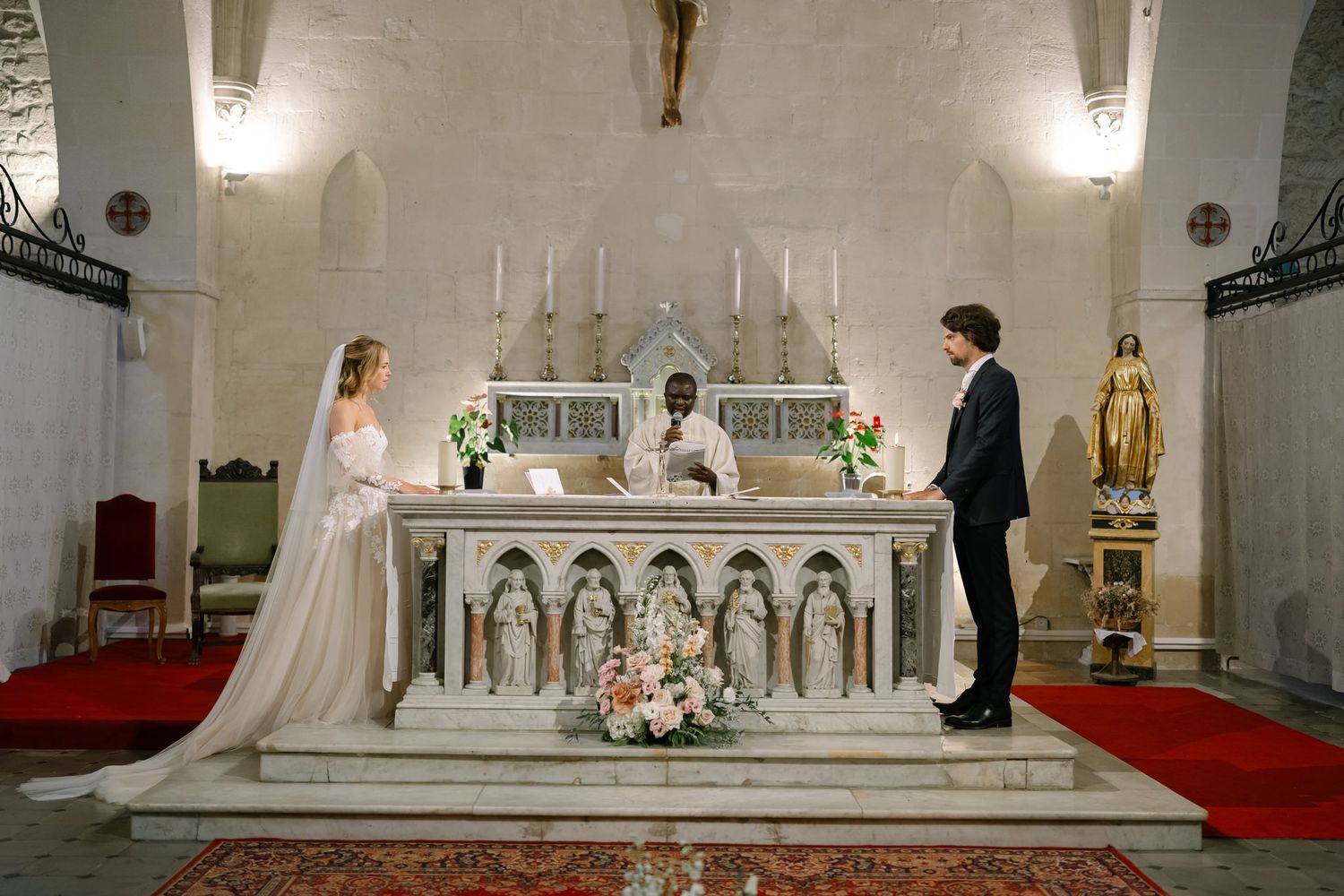 Traditional Catholic church altar decorated with white flowers and candles for a wedding ceremony.