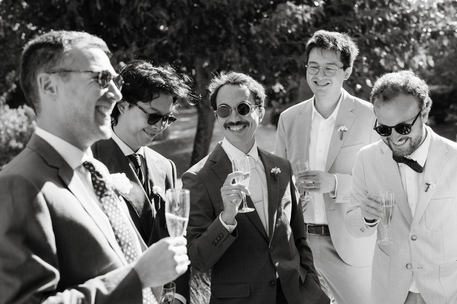 Wedding party members in formal attire mingling at an outdoor reception.