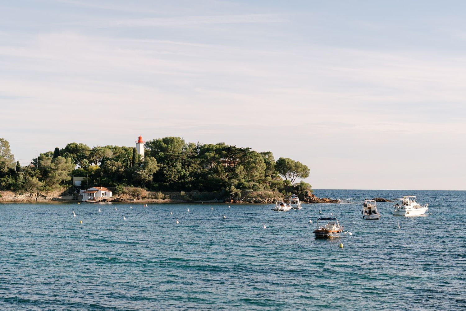 Scenic coastal view of a small island with boats in the distance.