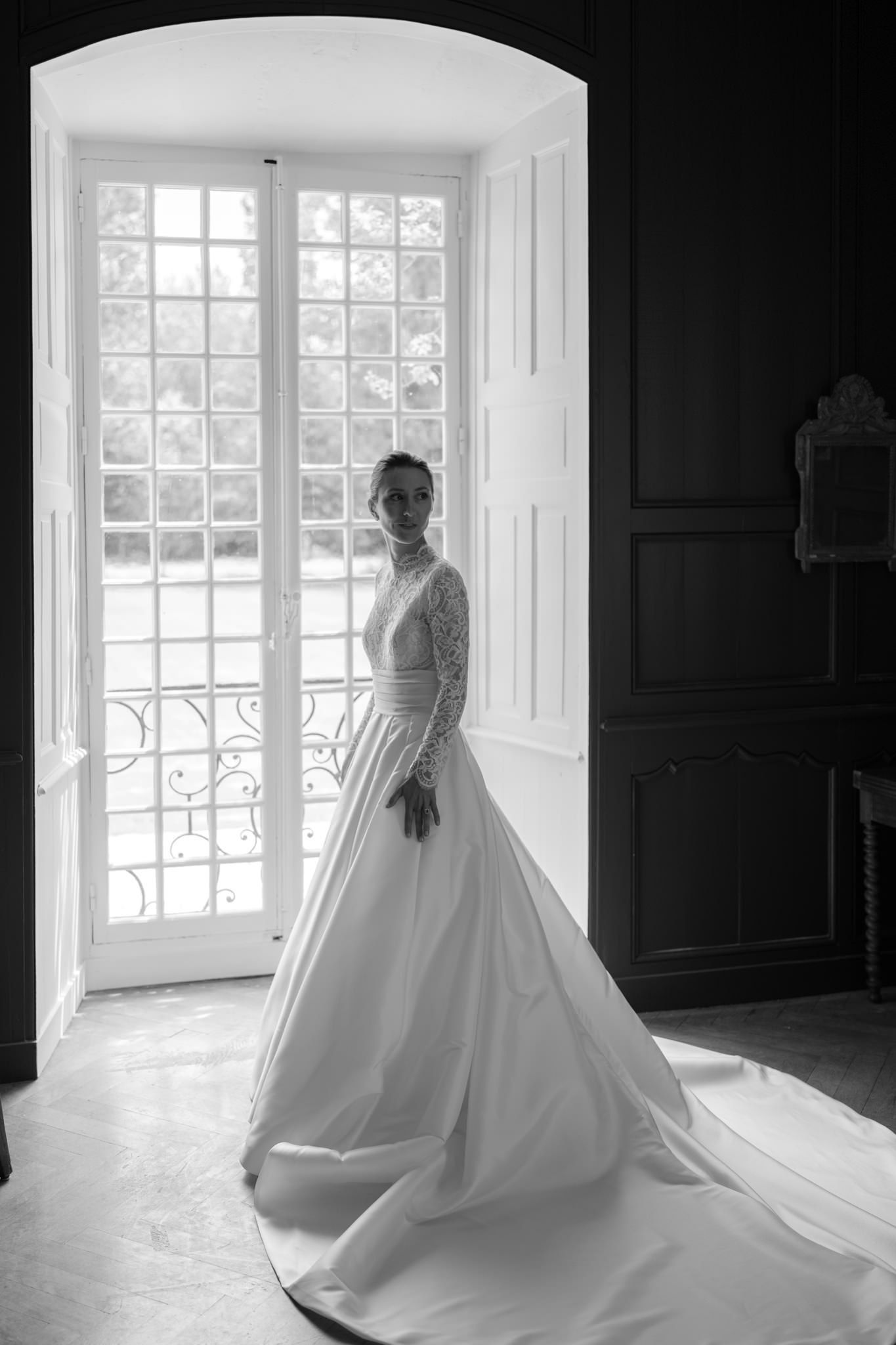 Wedding dress with full skirt silhouetted against bright window light.