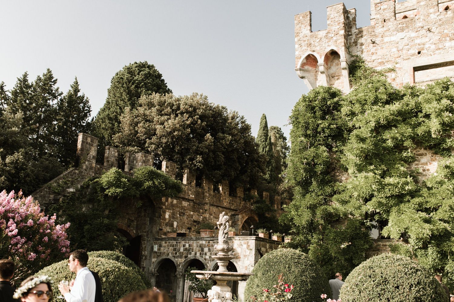 Historic stone villa with arched windows surrounded by manicured gardens and cypress trees in Tuscany.