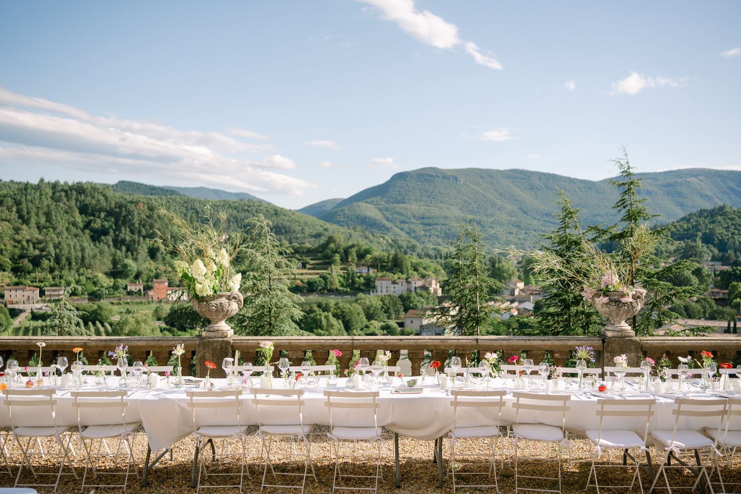 Panoramic mountain view of an outdoor wedding reception setup with white-clothed tables.