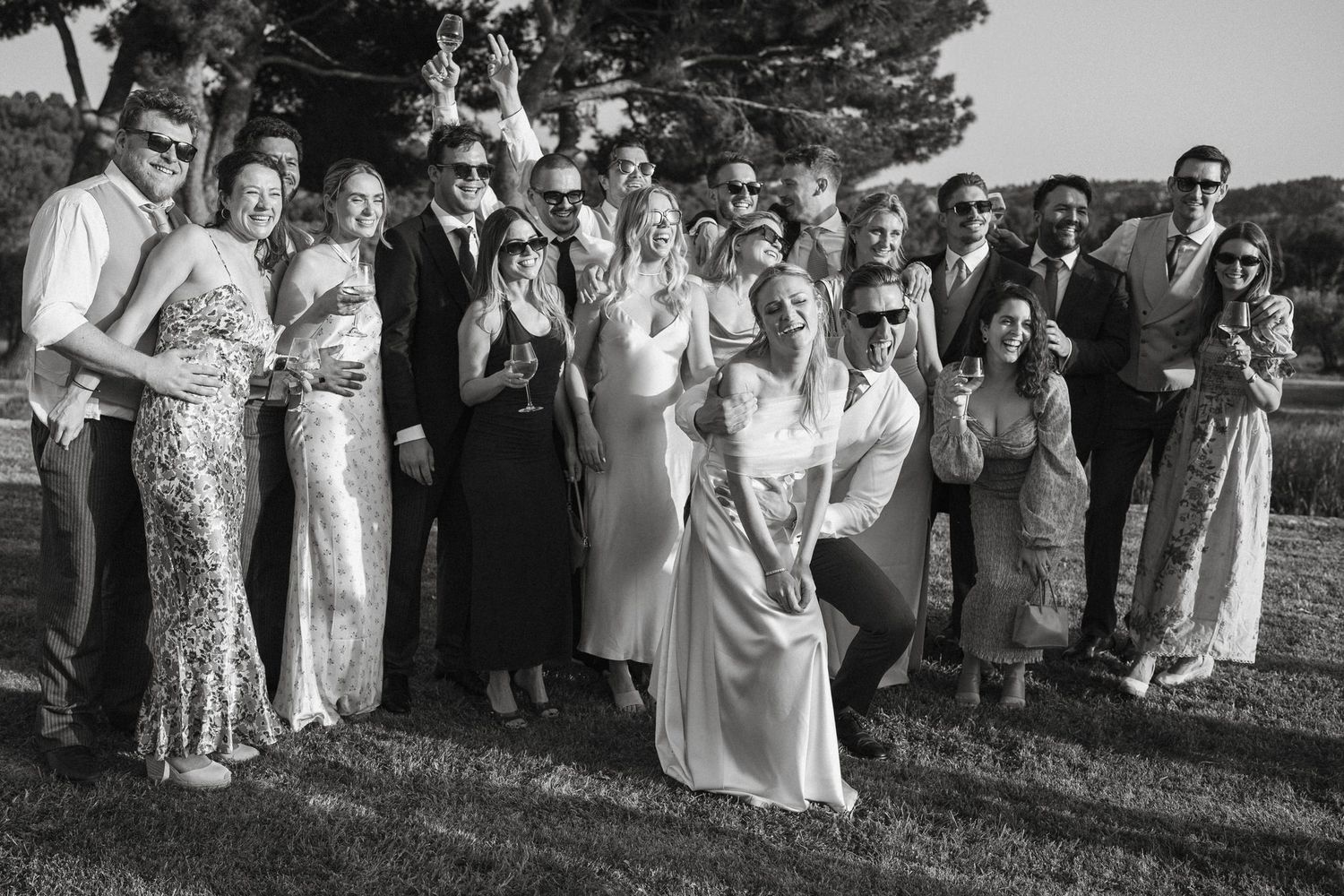 Large group of wedding guests gathered outdoors for formal photos.