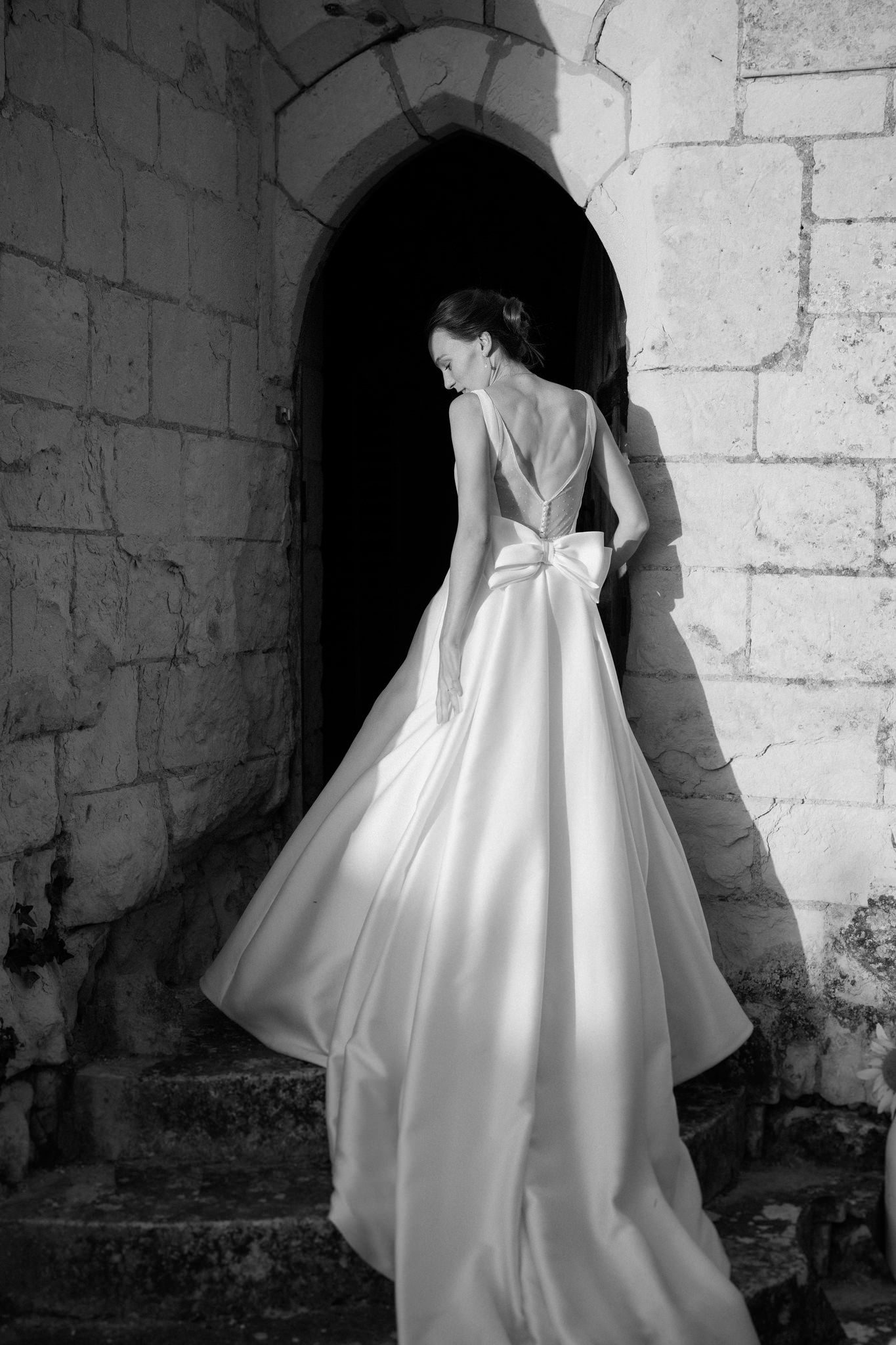 A dramatic black and white photo of a wedding dress against stone walls.