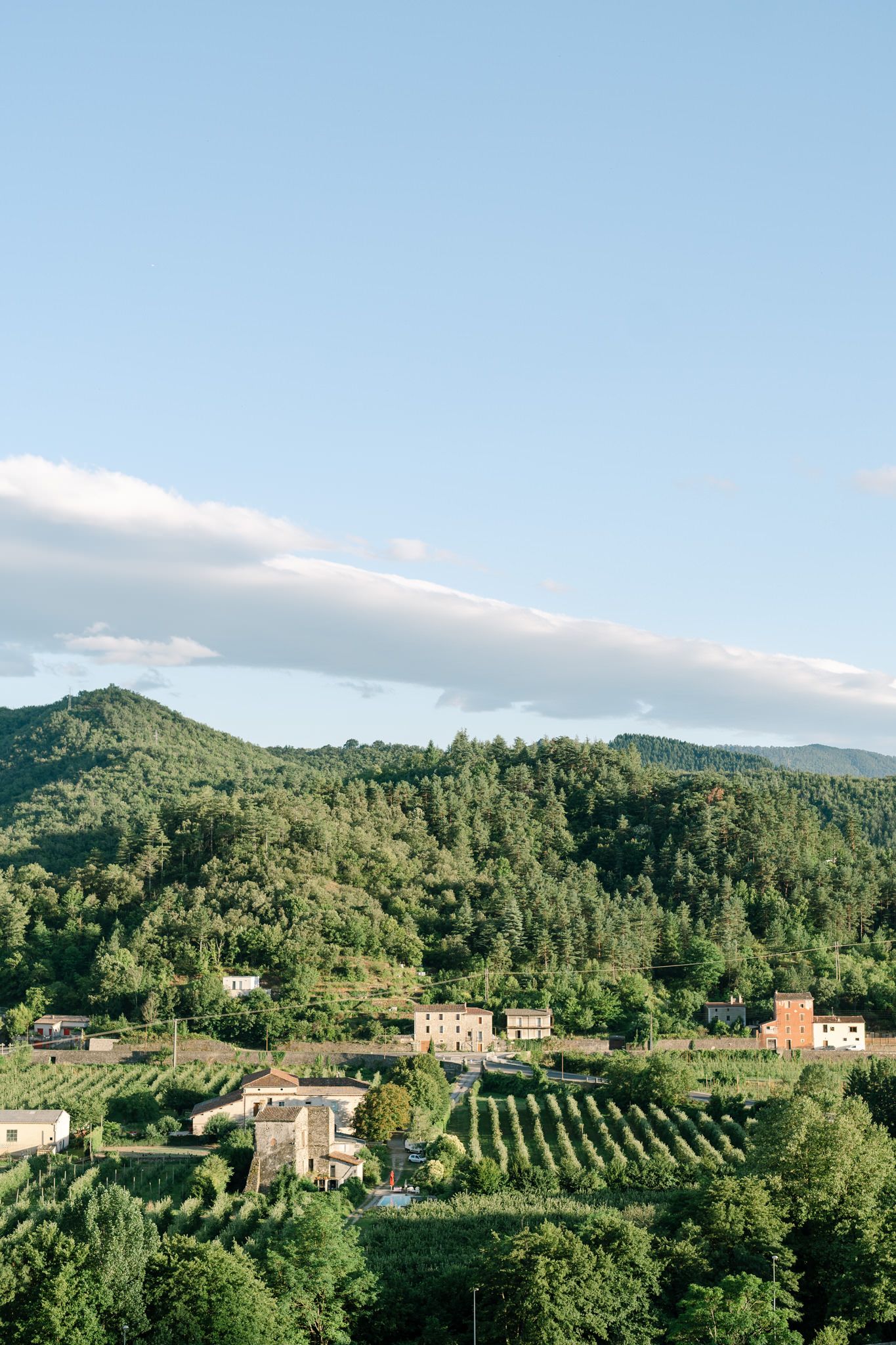 Scenic Tuscan countryside landscape with rolling hills, vineyards and stone buildings.
