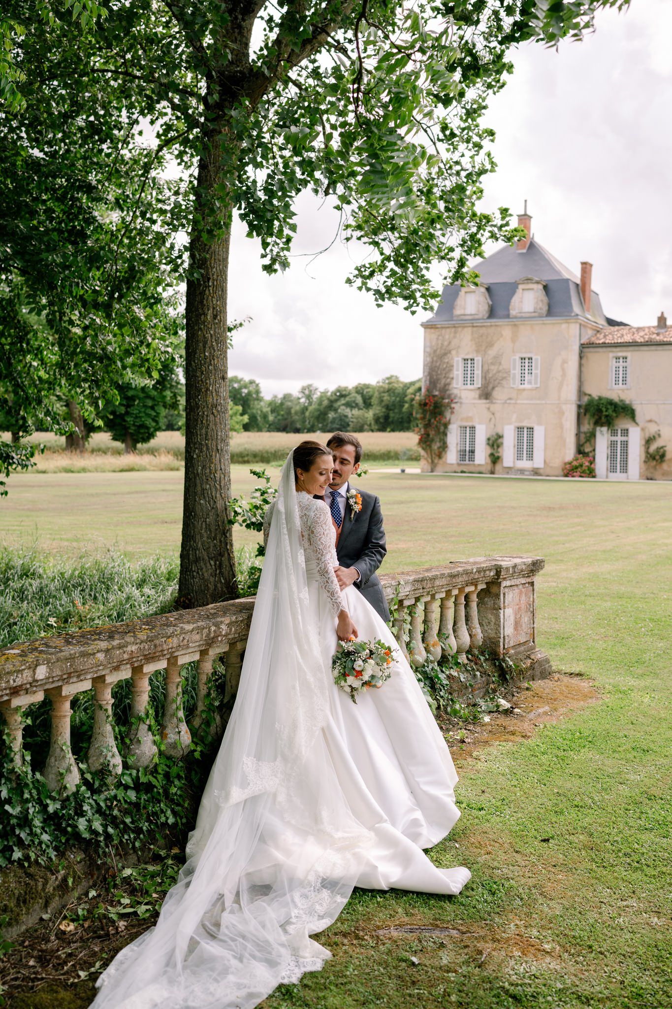 Romantic wedding portraits taken beside stone balustrade with chateau in background.