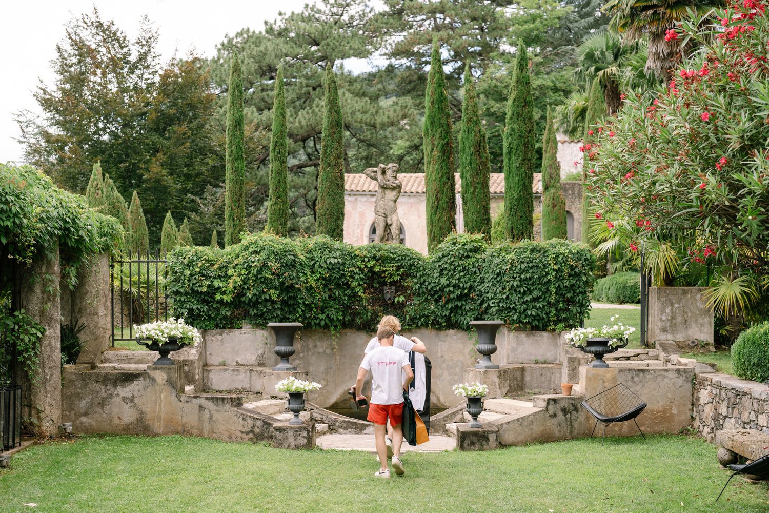 Elegant garden walkway with stone walls and red flowering plants at a luxury estate.